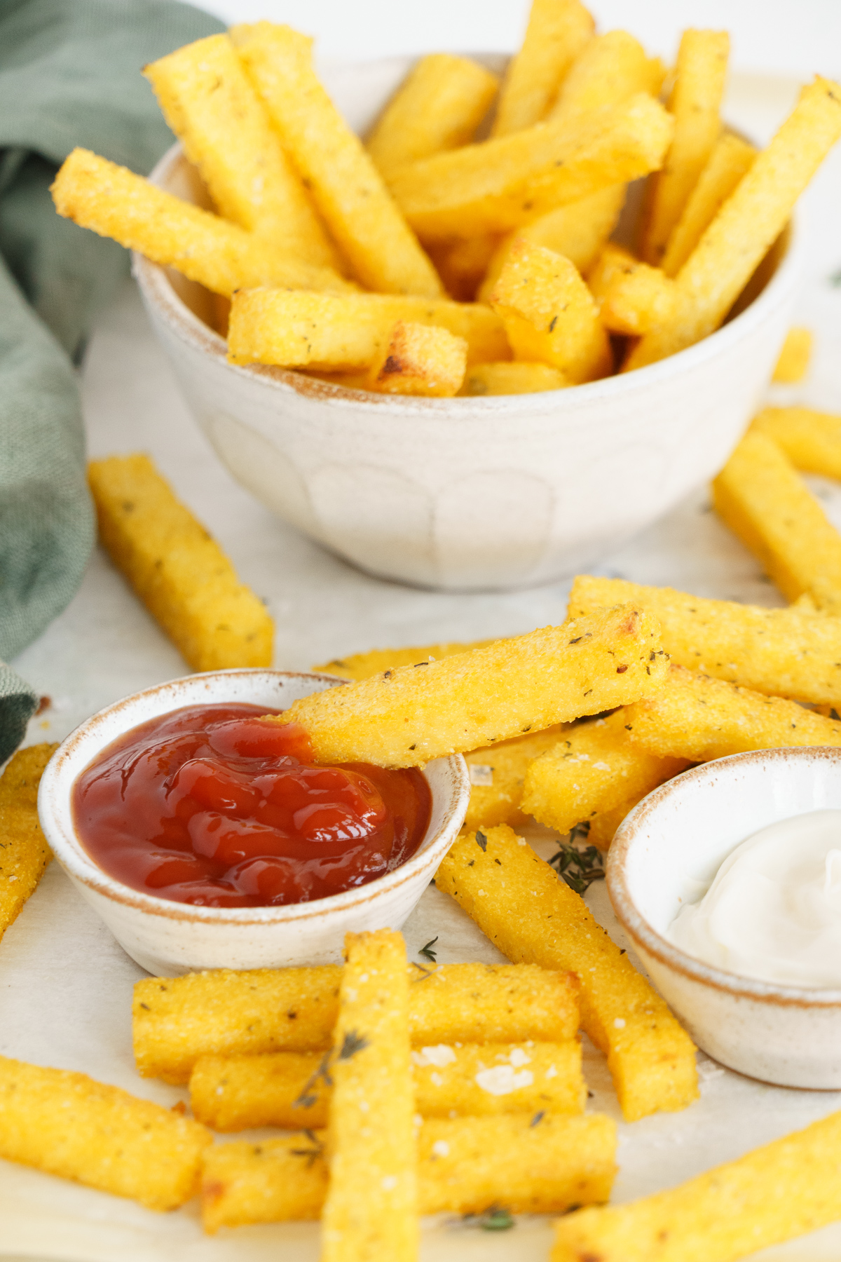 Close up of polenta fries with dippings around like ketchup and mayonnaise