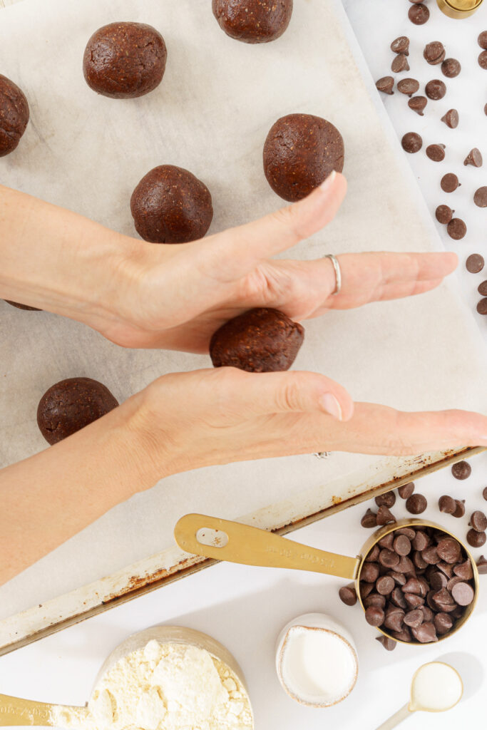 image of hands pressing a scoop of cookie dough to form it into a ball