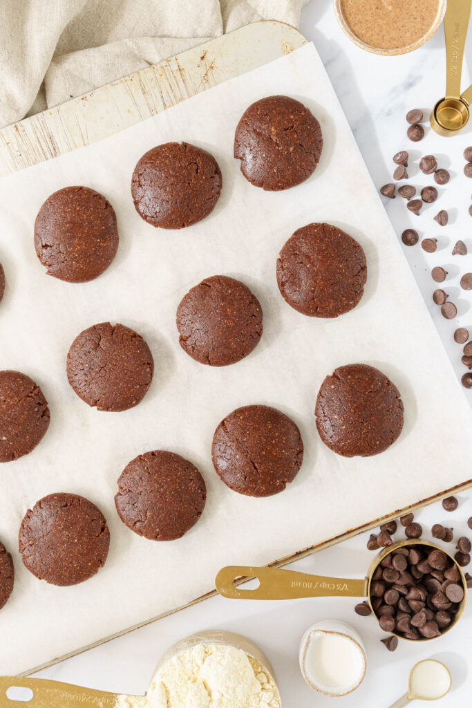 image of circular cookies made from cookie dough, flattened and arranged in rows on parchment paper