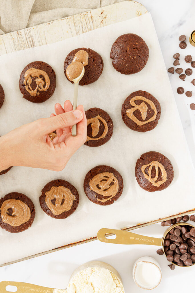 an image of a hand is gently pouring a topping onto a circle of cookie dough