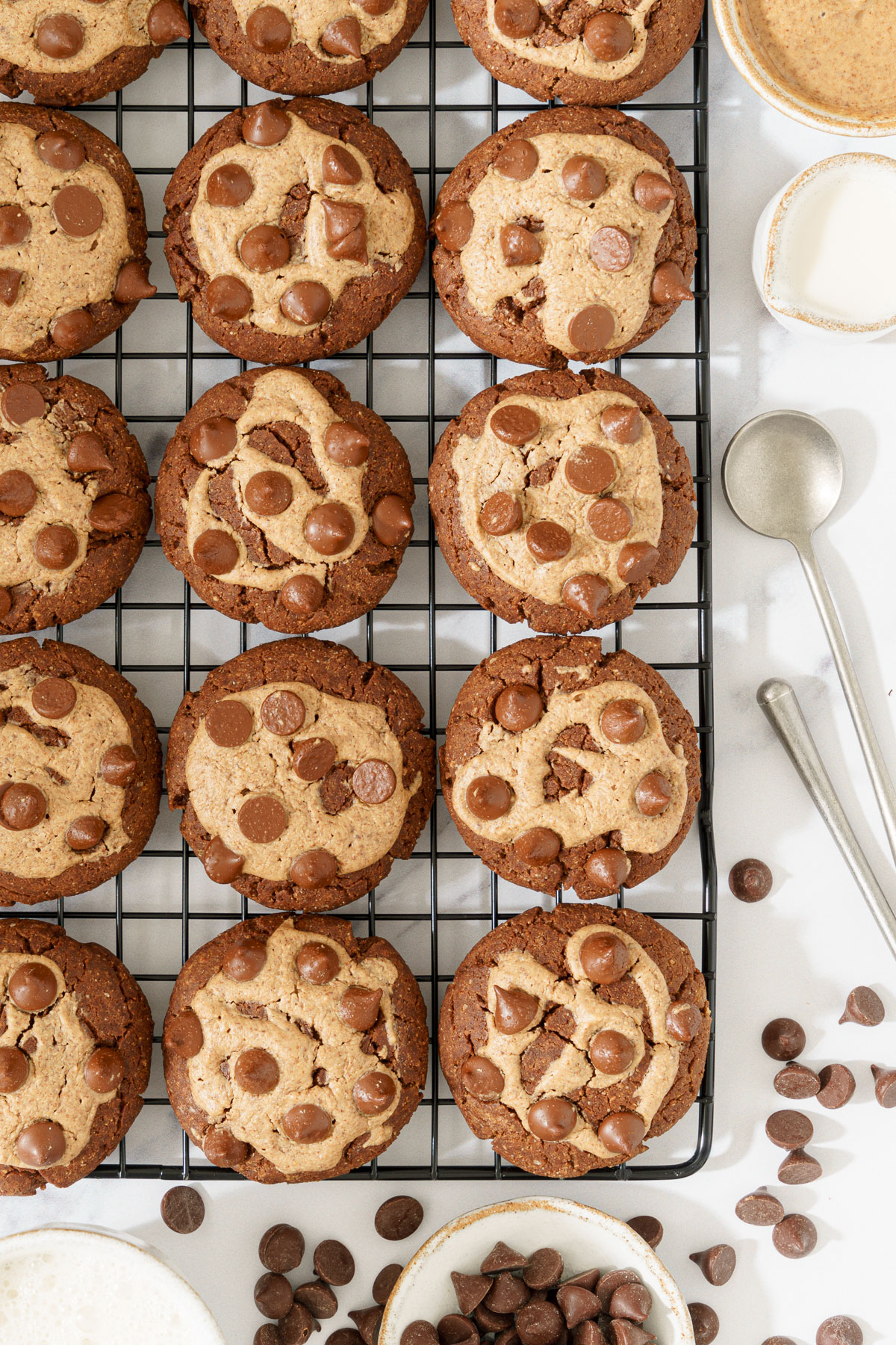 top-down view image of a row of freshly baked Chocolate Chickpea Flour Cookies arranged on a cooling rack, with a scattering of chocolate chips around them.