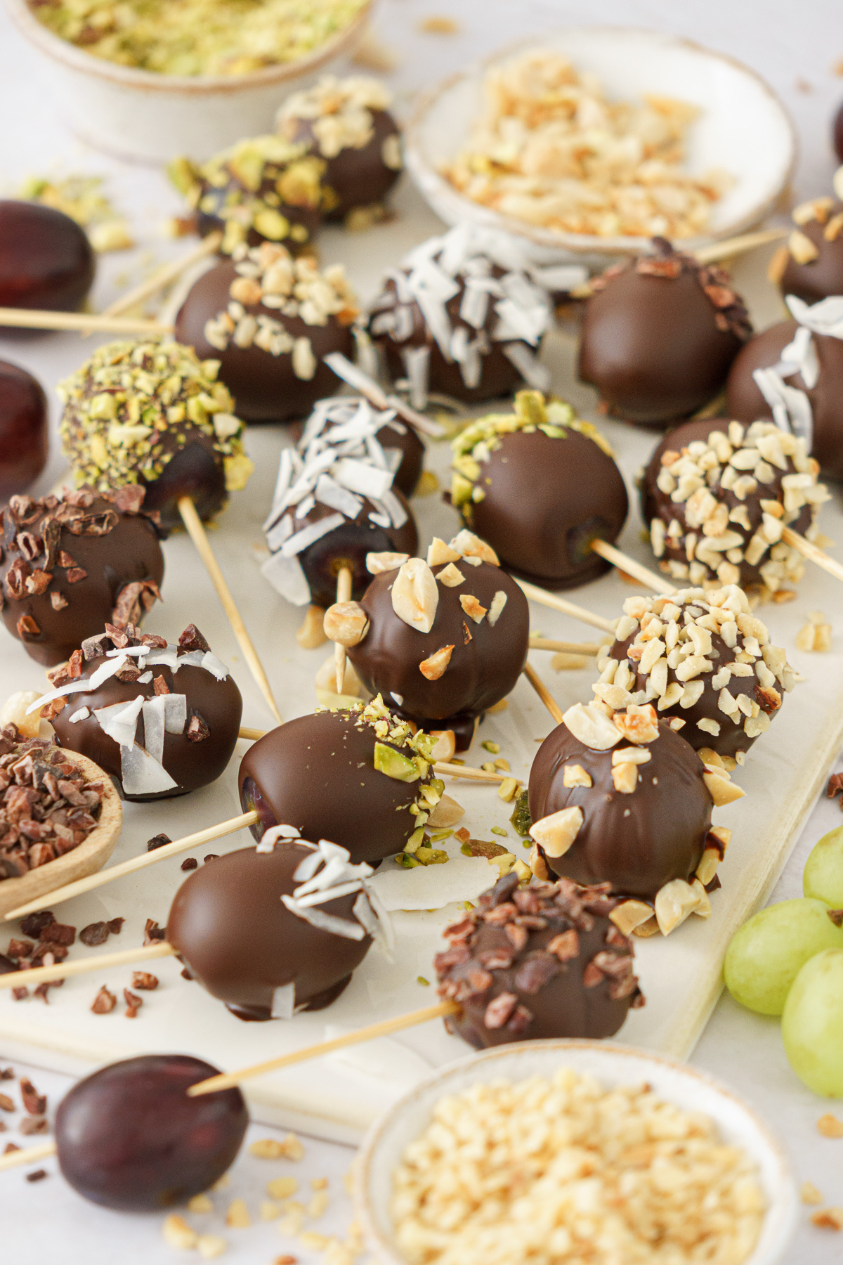 Close up of chocolate covered grapes on a ceramic board.