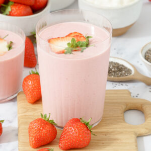 Glass filled with a strawberry cottage cheese smoothie, garnished with fresh strawberries.