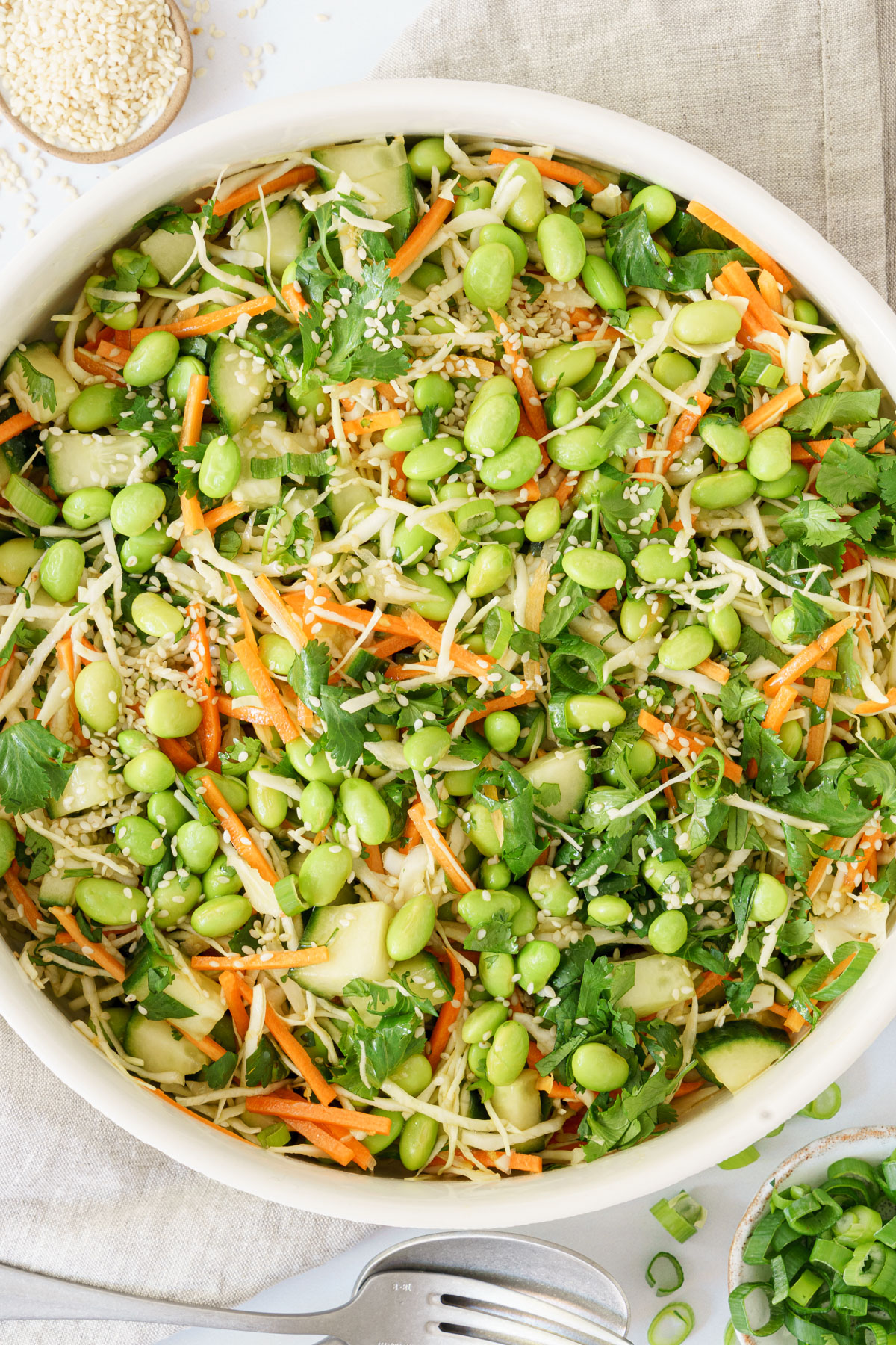 top-down close-up image showing a mixture of edamame salad ingredients sprinkled with sesame seeds.
