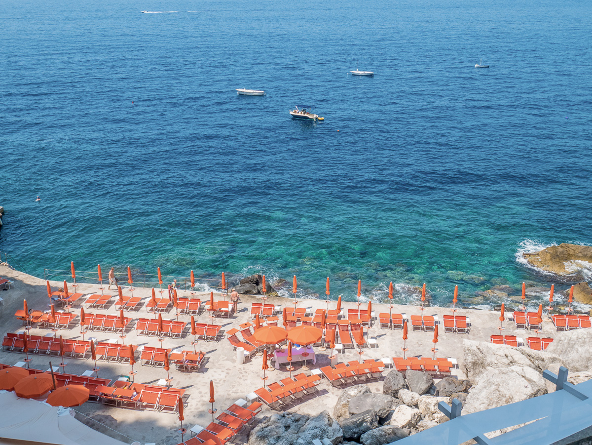 Gavitella Beach with sunbeds at Praiano cliffs in the Amalfi coast, Italy.