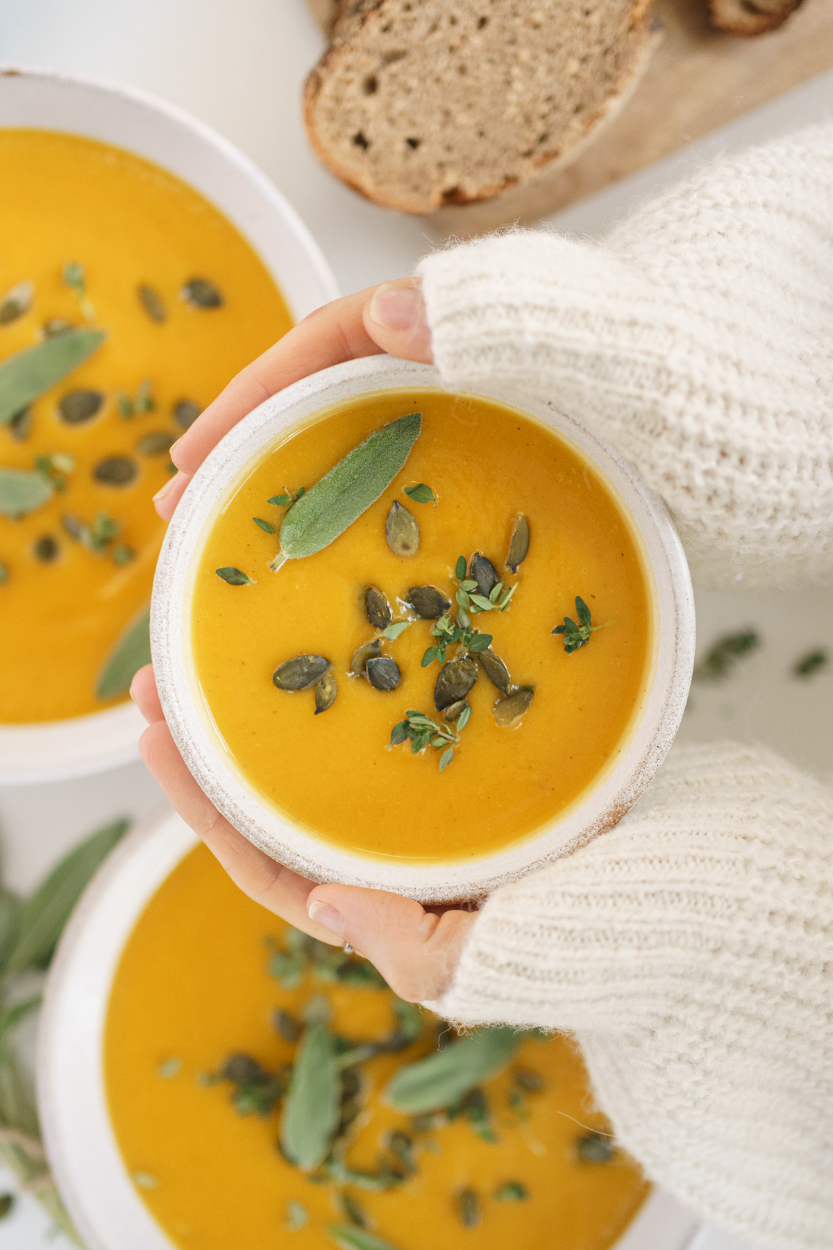 Hands holding a warm bowl of butternut squash soup