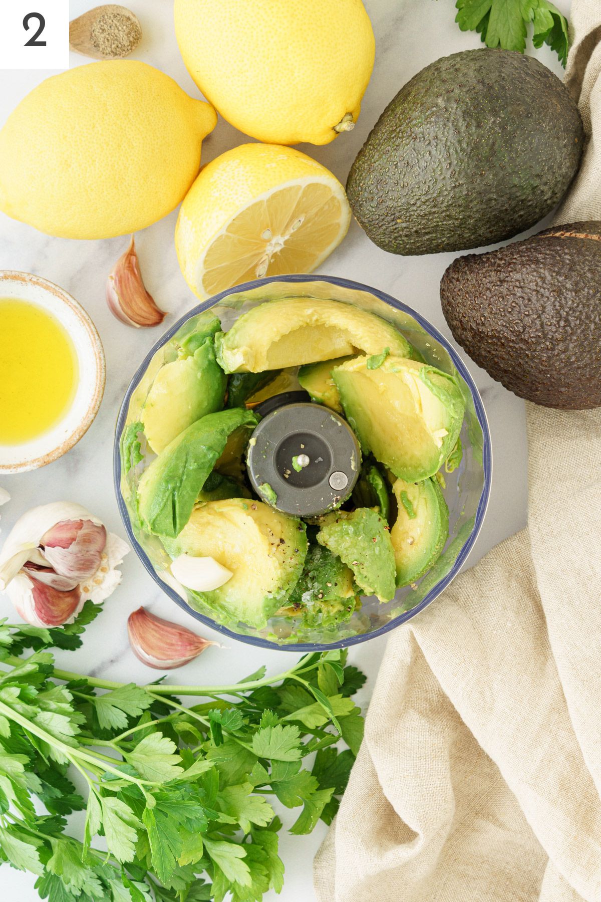 Food processor filled with scooped-out avocados.