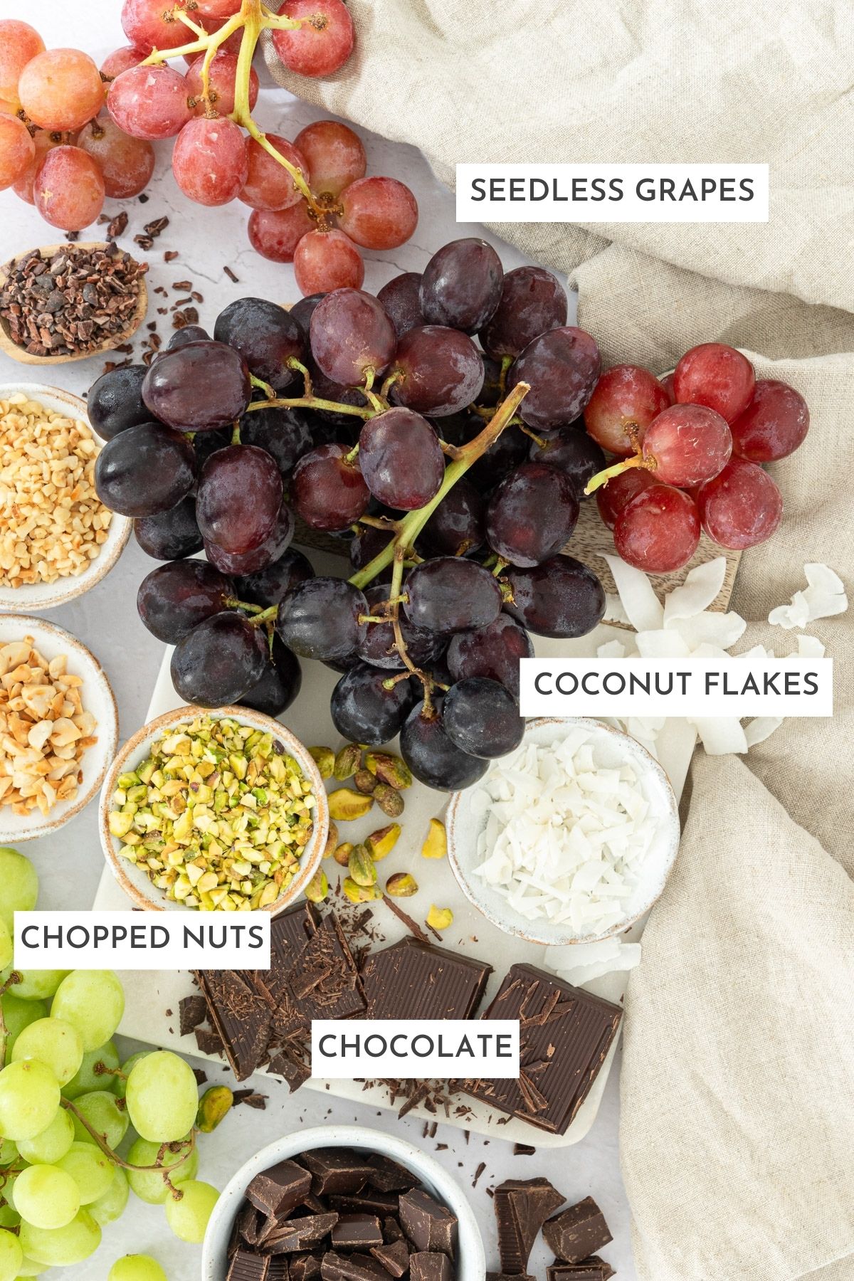 Ingredients to make chocolate covered grapes: grapes, chocolate, chopped nuts, coconut flakes.