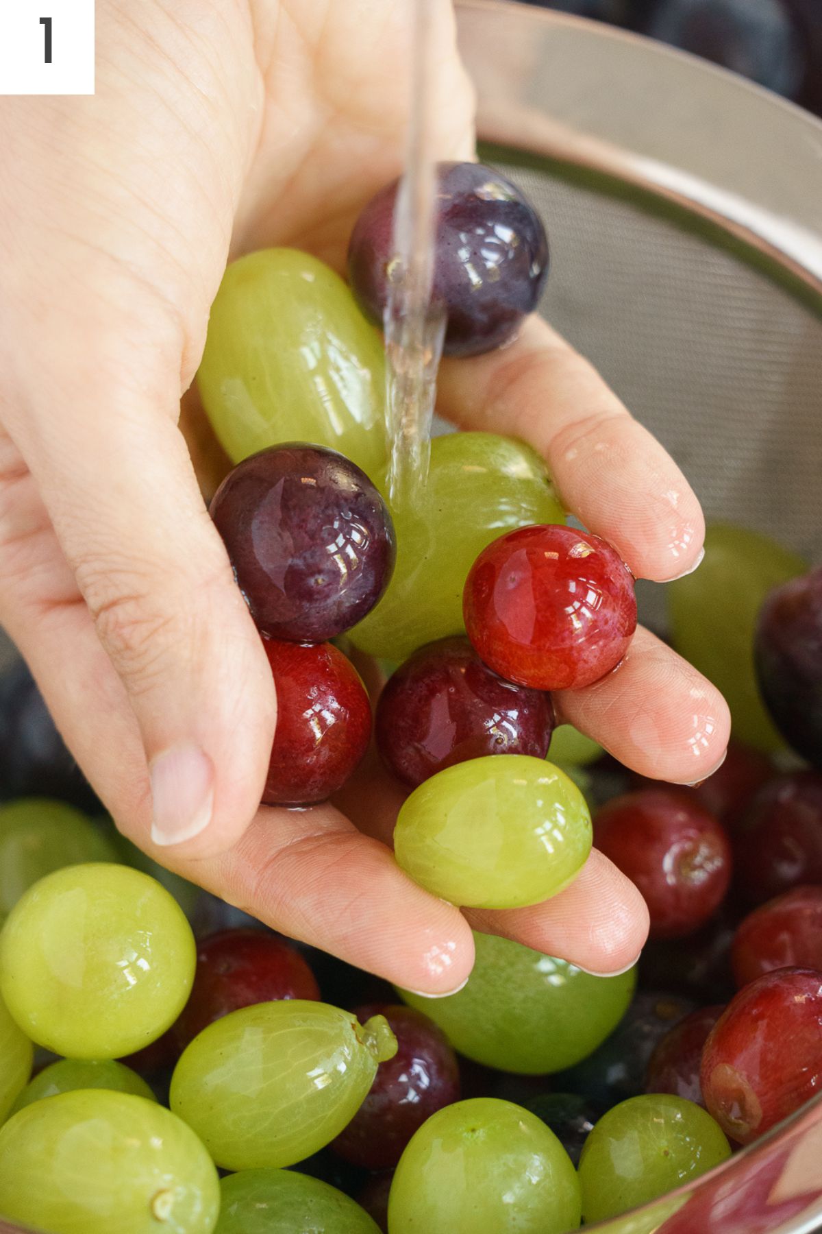 Hand washing grapes under running water.