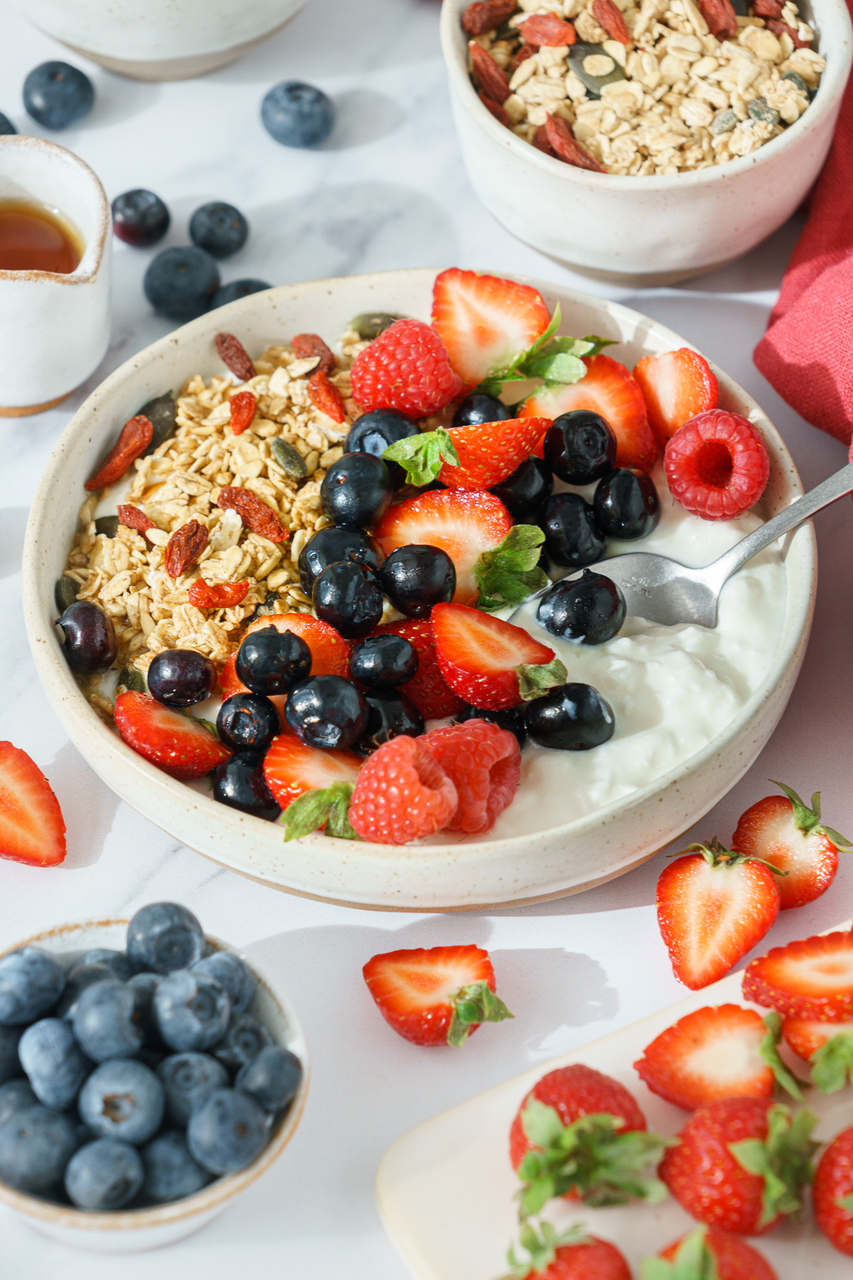 Bowl containing a mix of cottage cheese, fresh strawberries, blueberries, raspberries, and granola.