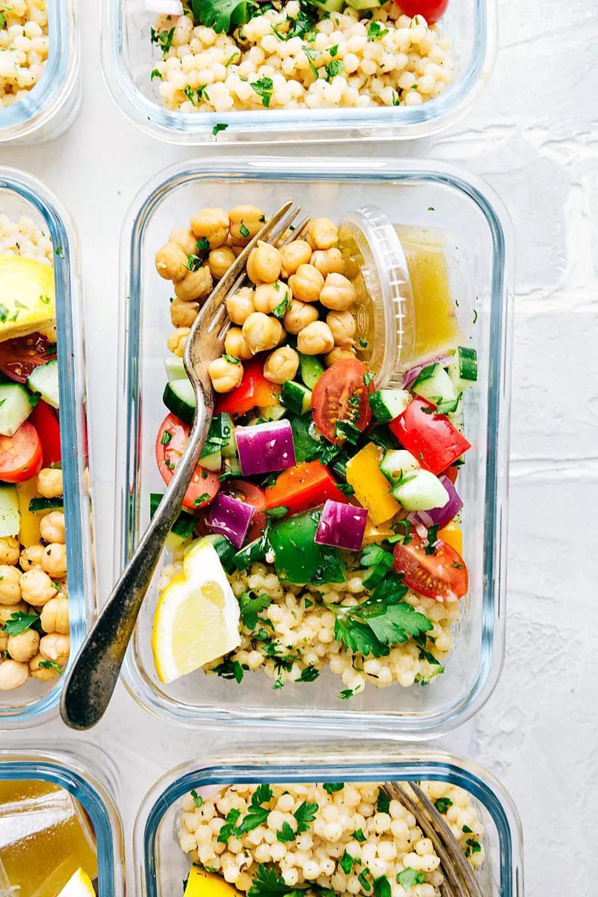 Greek couscous salad in a glass meal prep container.