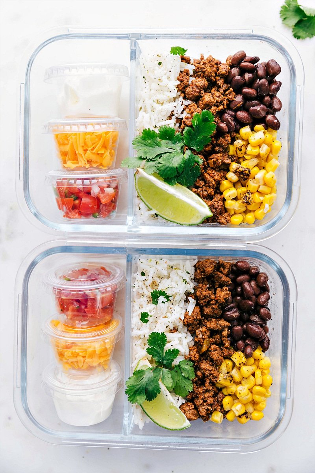 Taco bowls in two glass meal prep containers.