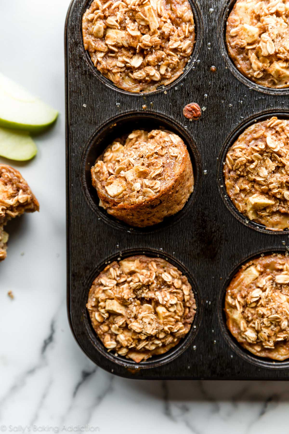 Cooked apple and cinnamon baked oatmeal cups in a muffin tin.