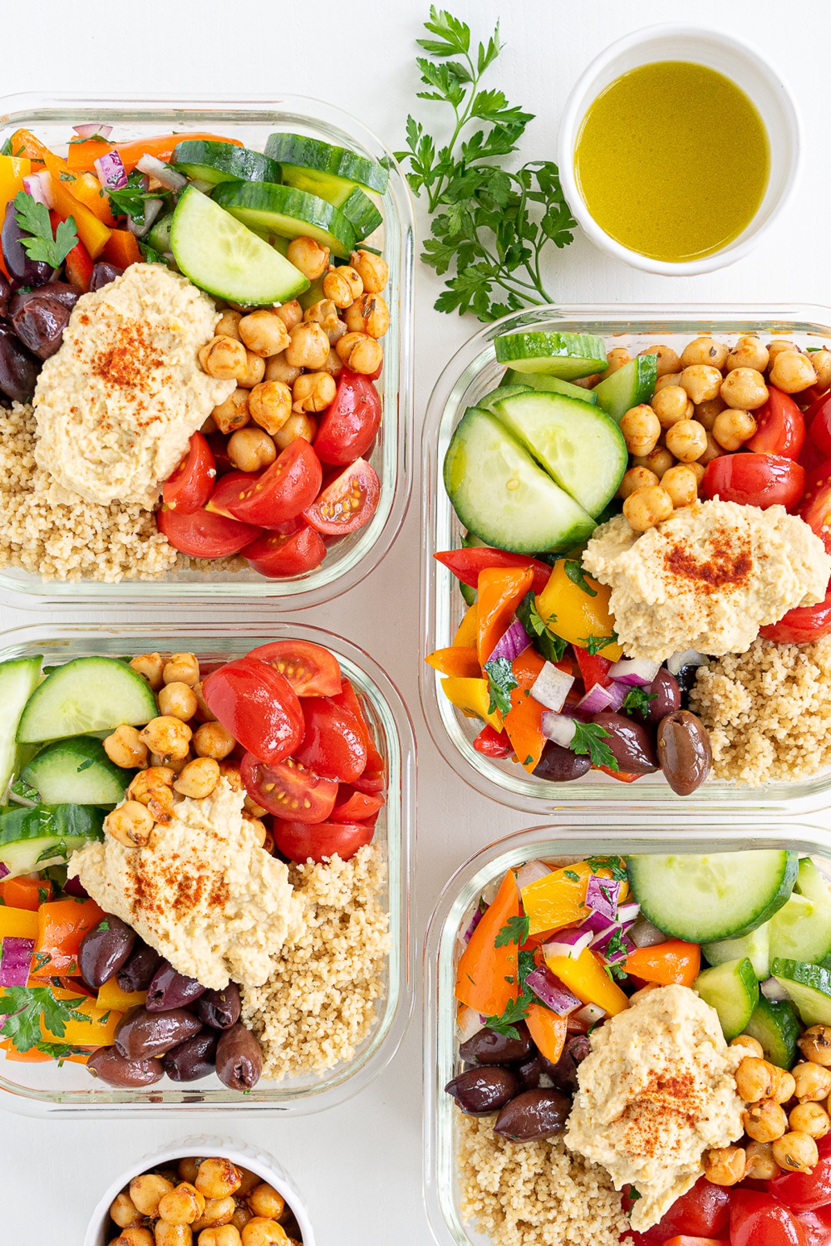 Four glass meal prep container filled with mediterranean salad.