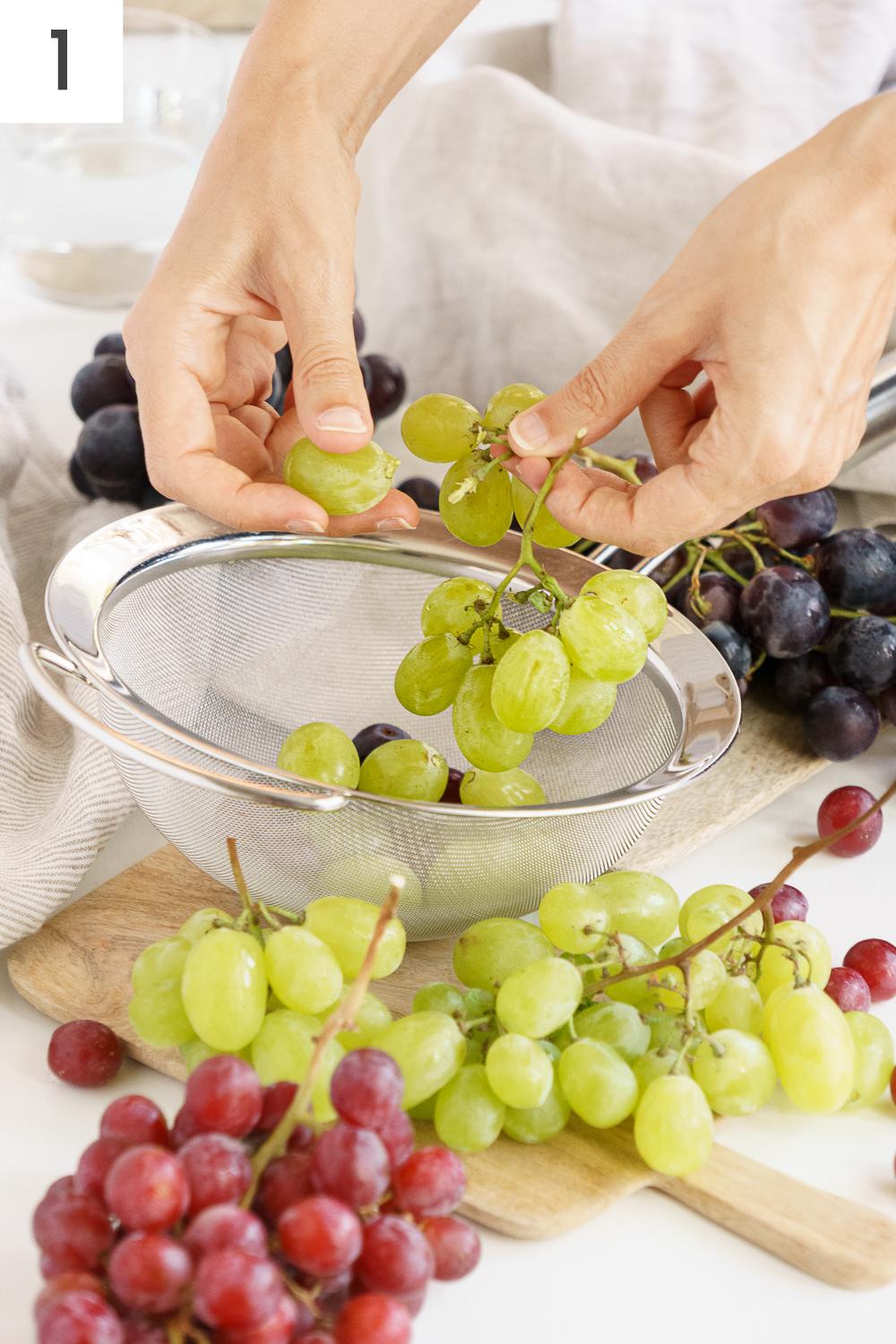 Hands removing grapes from stems.