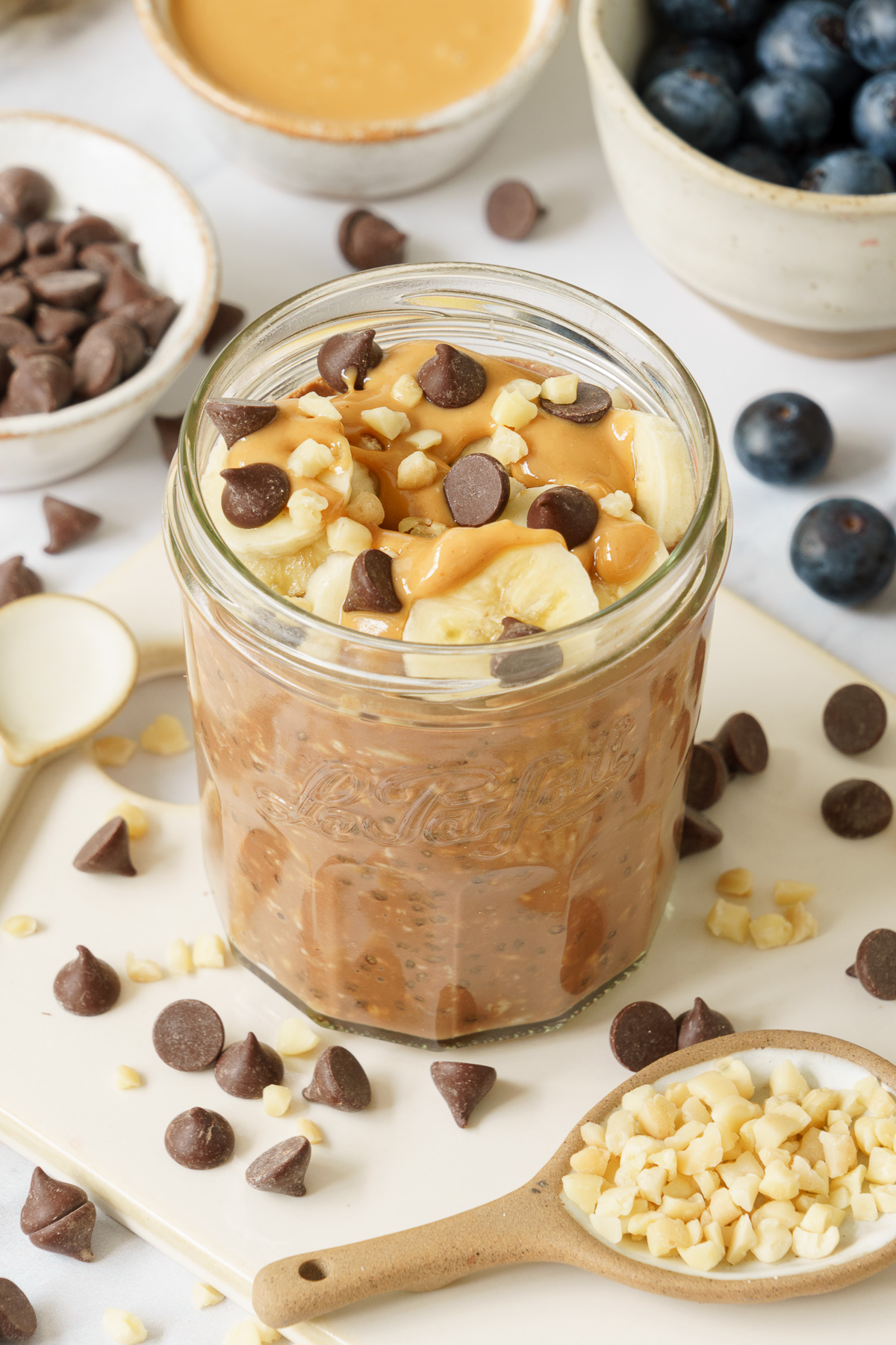 A jar of overnight oats topped with chocolate chips, peanut butter and fresh banana.