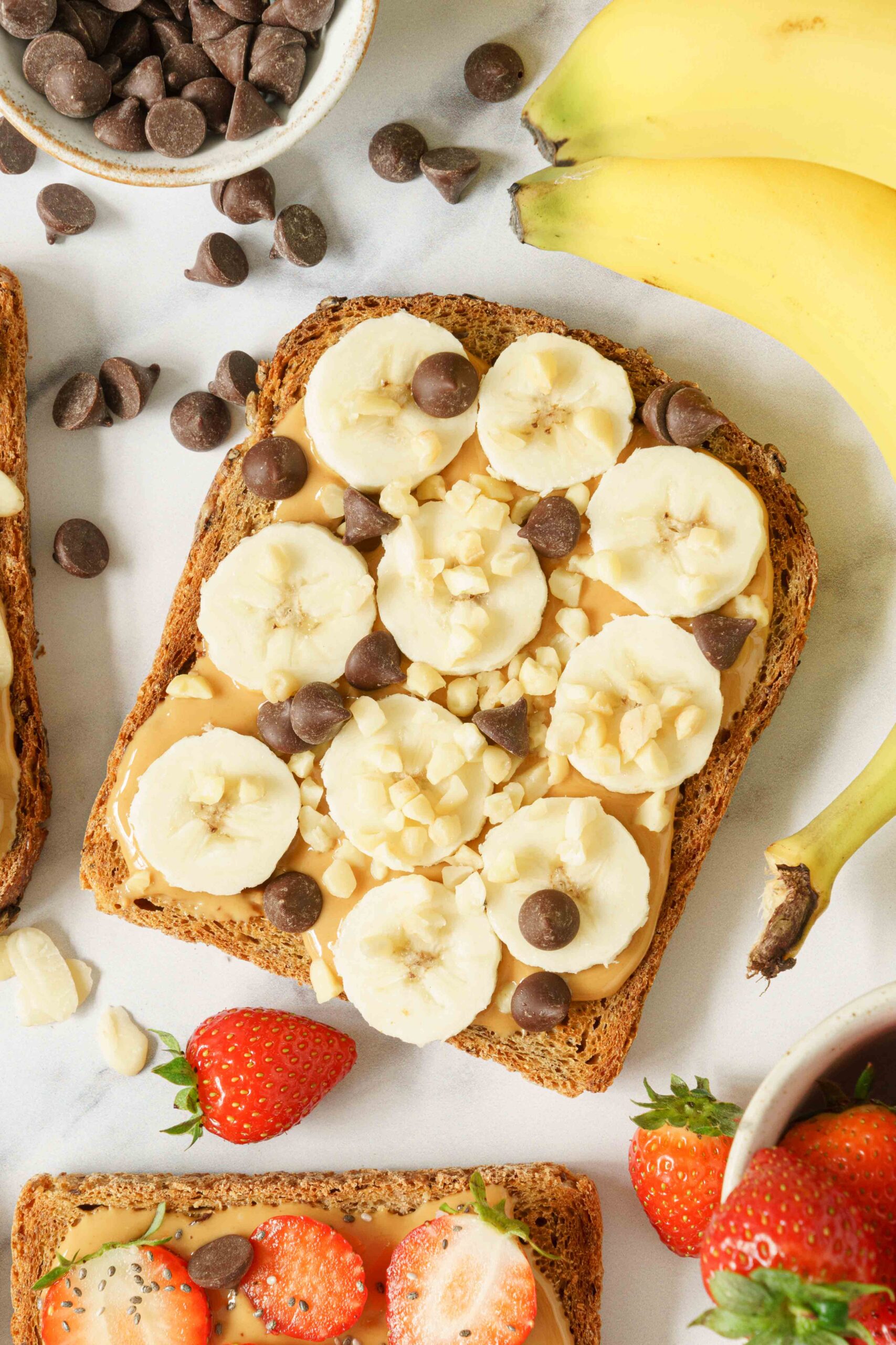 One single slice of bread spread with peanut butter and topped with bananas, chocolate nibs, and crushed nuts.