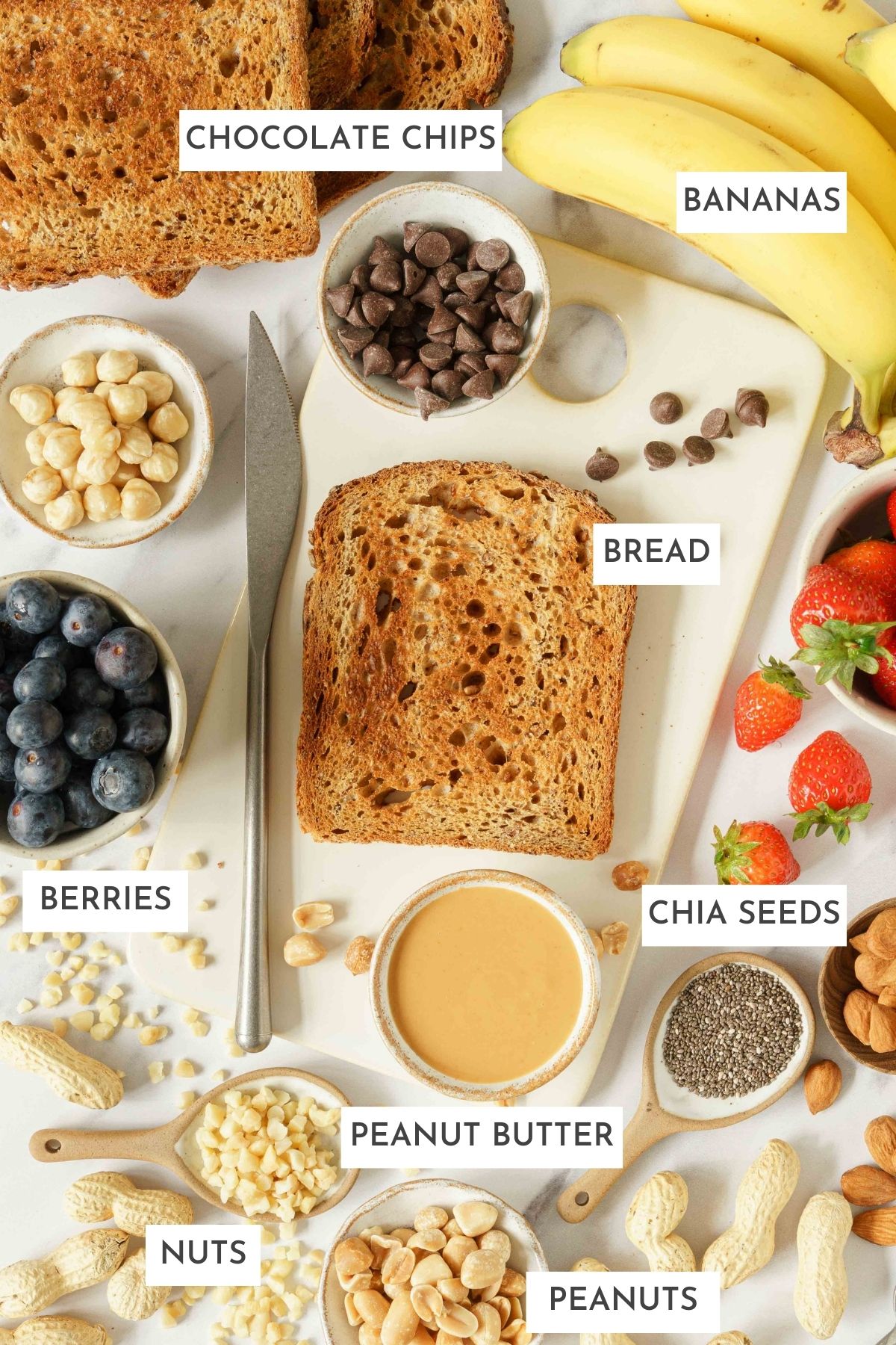 All ingredients laid out on a table: bread, chia seeds, berries, pea nut butter, nuts, and peanuts.