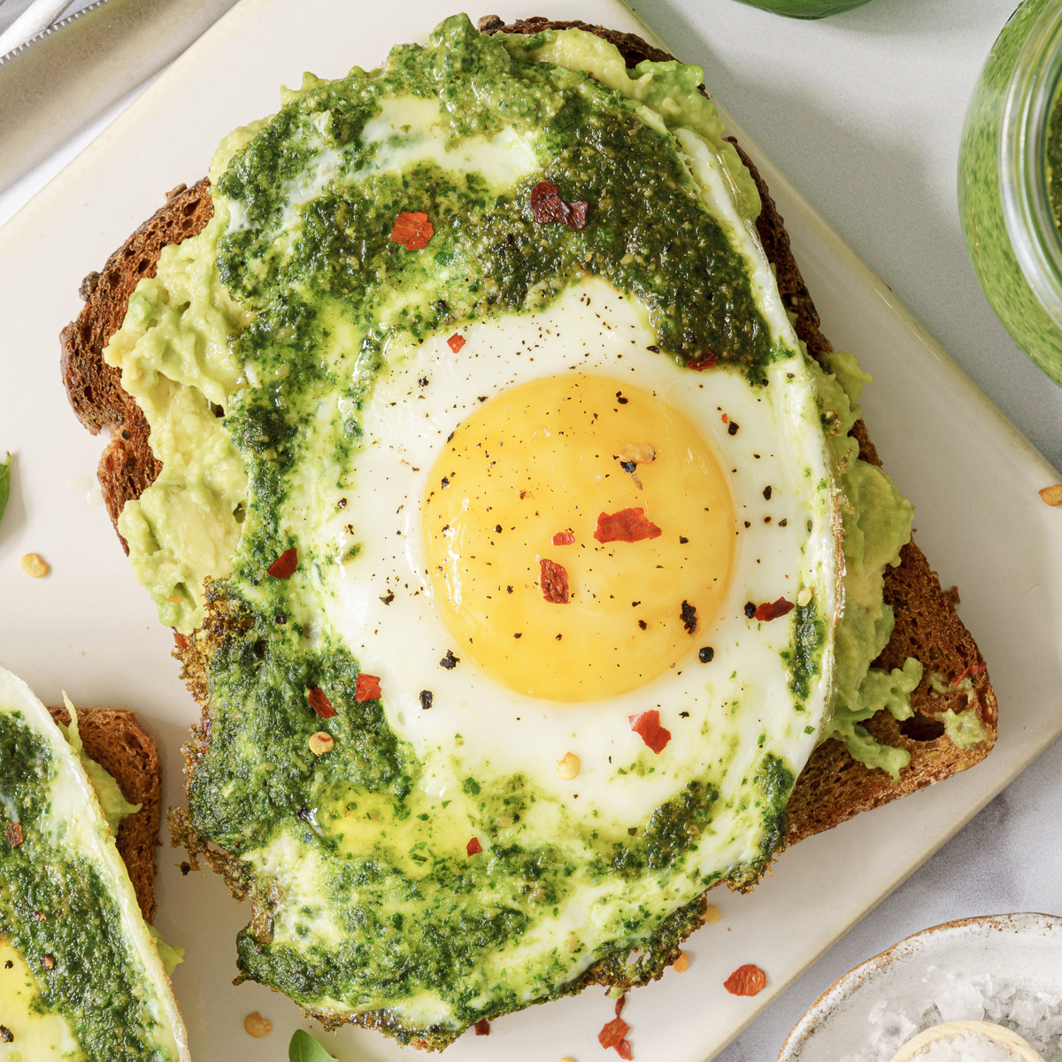 A single slice of bread with mashed potato topped with pesto egg.