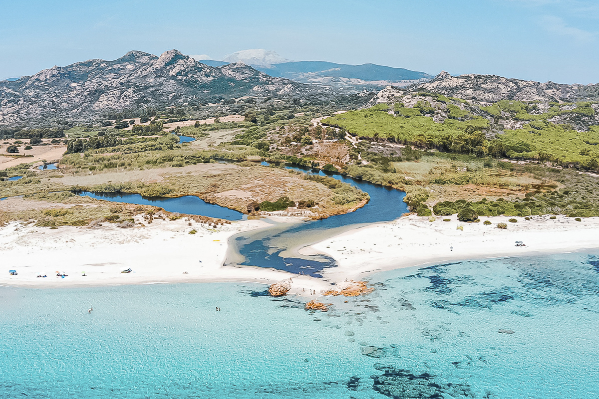 Bird's eye view of a sea landscape with a river mouth and green meadow, Berchida, Sardinia.