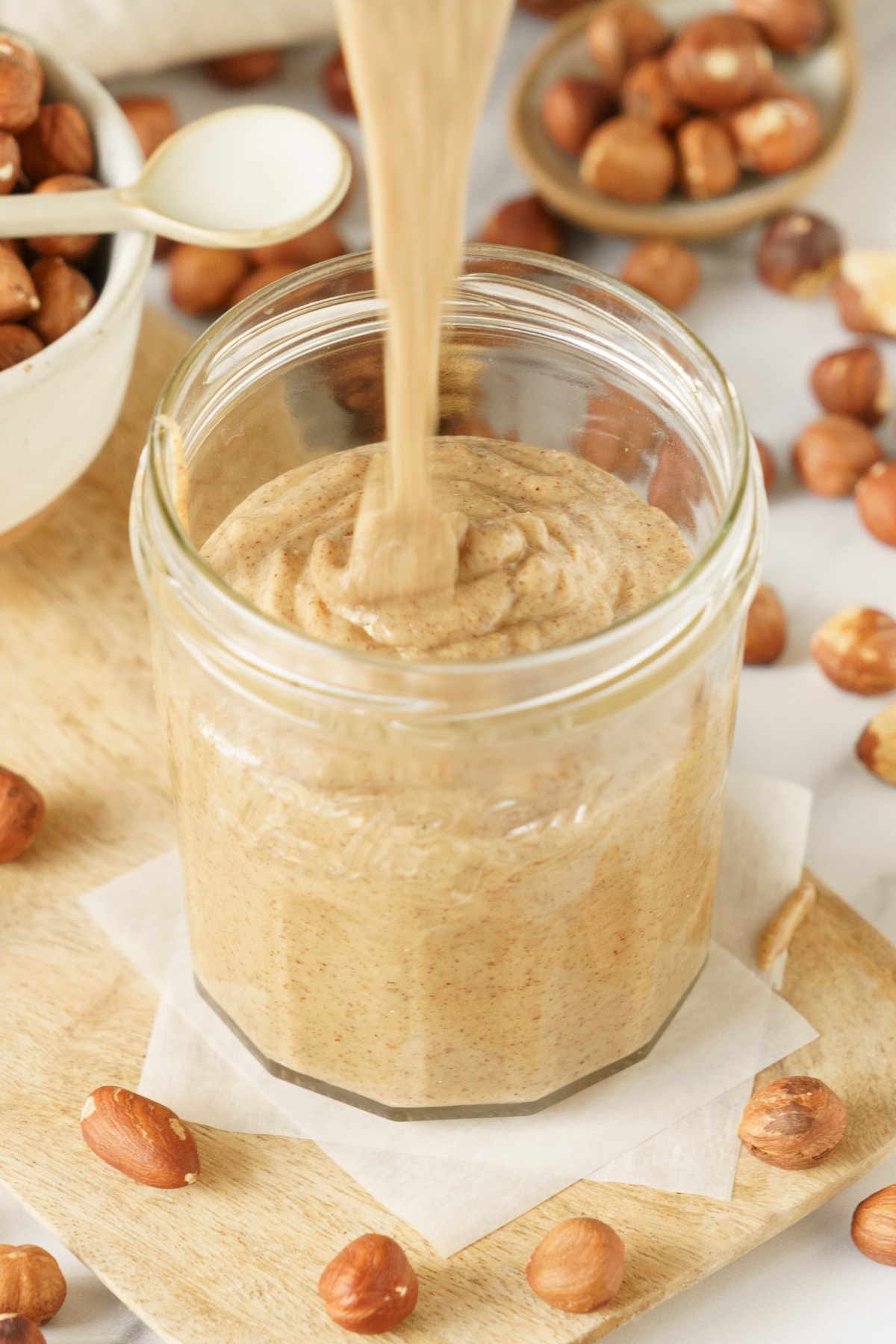Transferring homemade hazelnut butter in glass jar.
