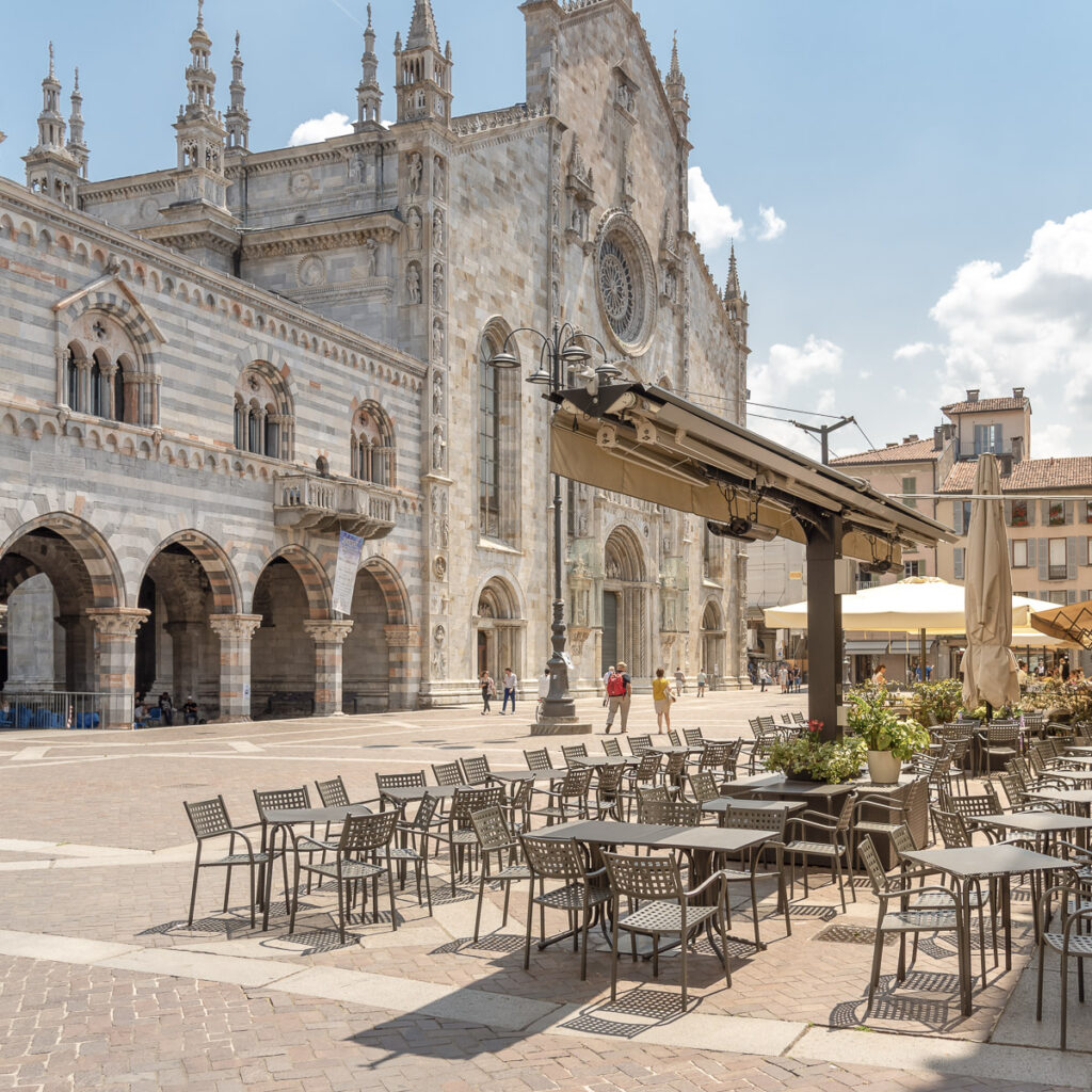 View of Duomo square with traditional Italian street cafe in the historic center of Como, Italy.