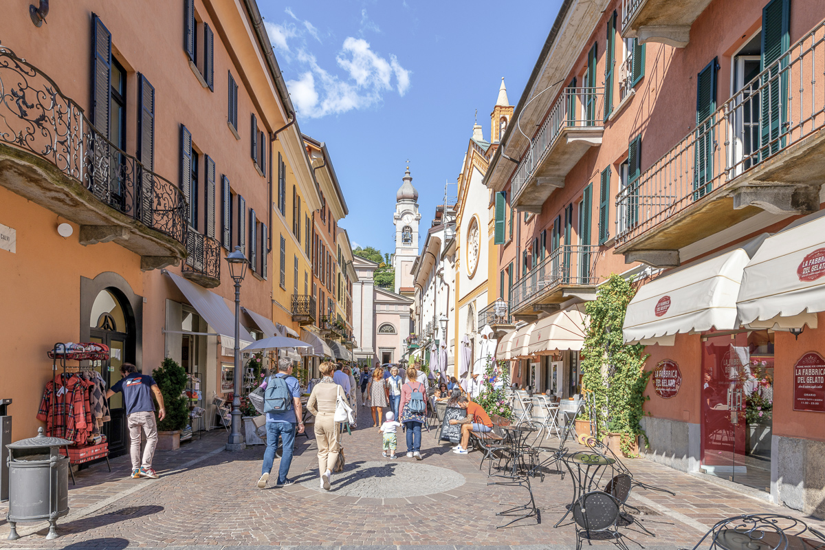 A colorful narrow street of shops and cafes in the medieval old town center of Menaggio, Italy, on the shores of Lake Como.