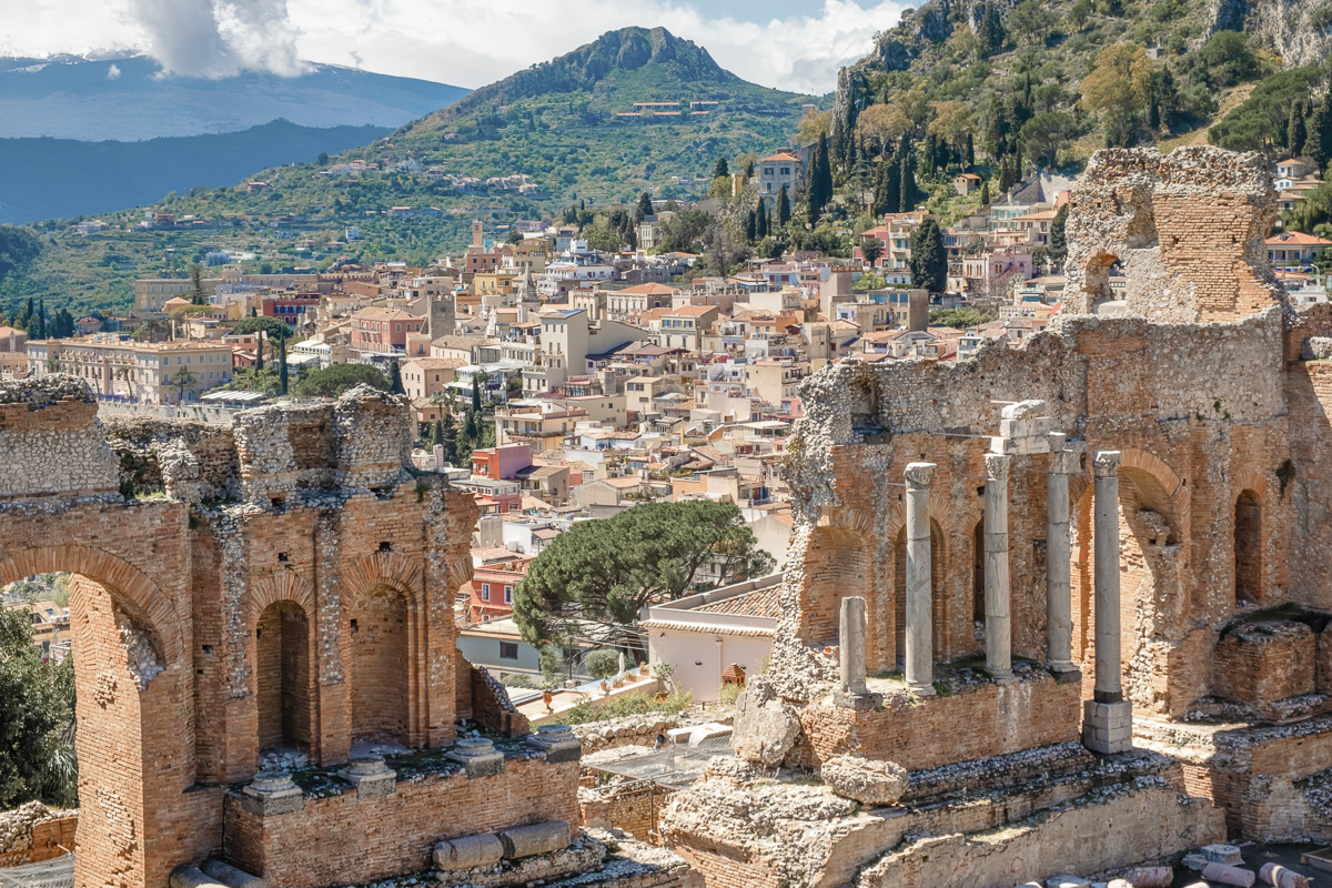 Ruins of ancient Greek theater in Taormina old town and mountain in background.