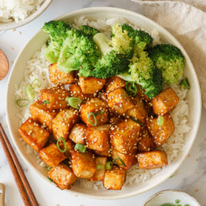 A bowl of rice topped with crispy teriyaki tofu and broccoli.