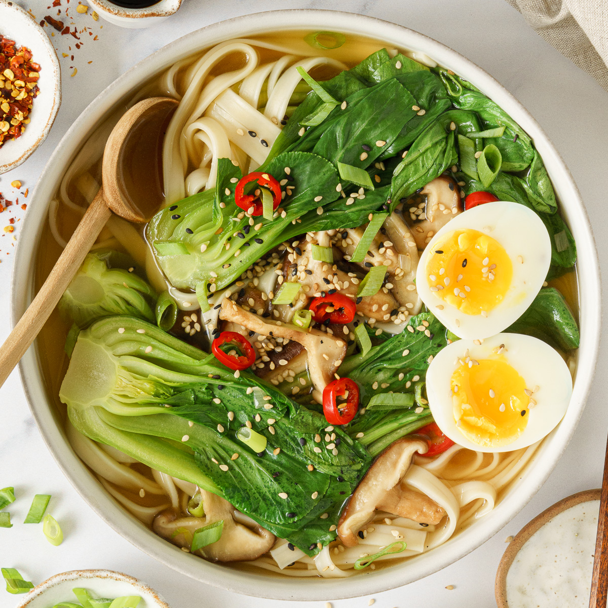 A bowl of bok choy soup topped with egg and sesame seeds.