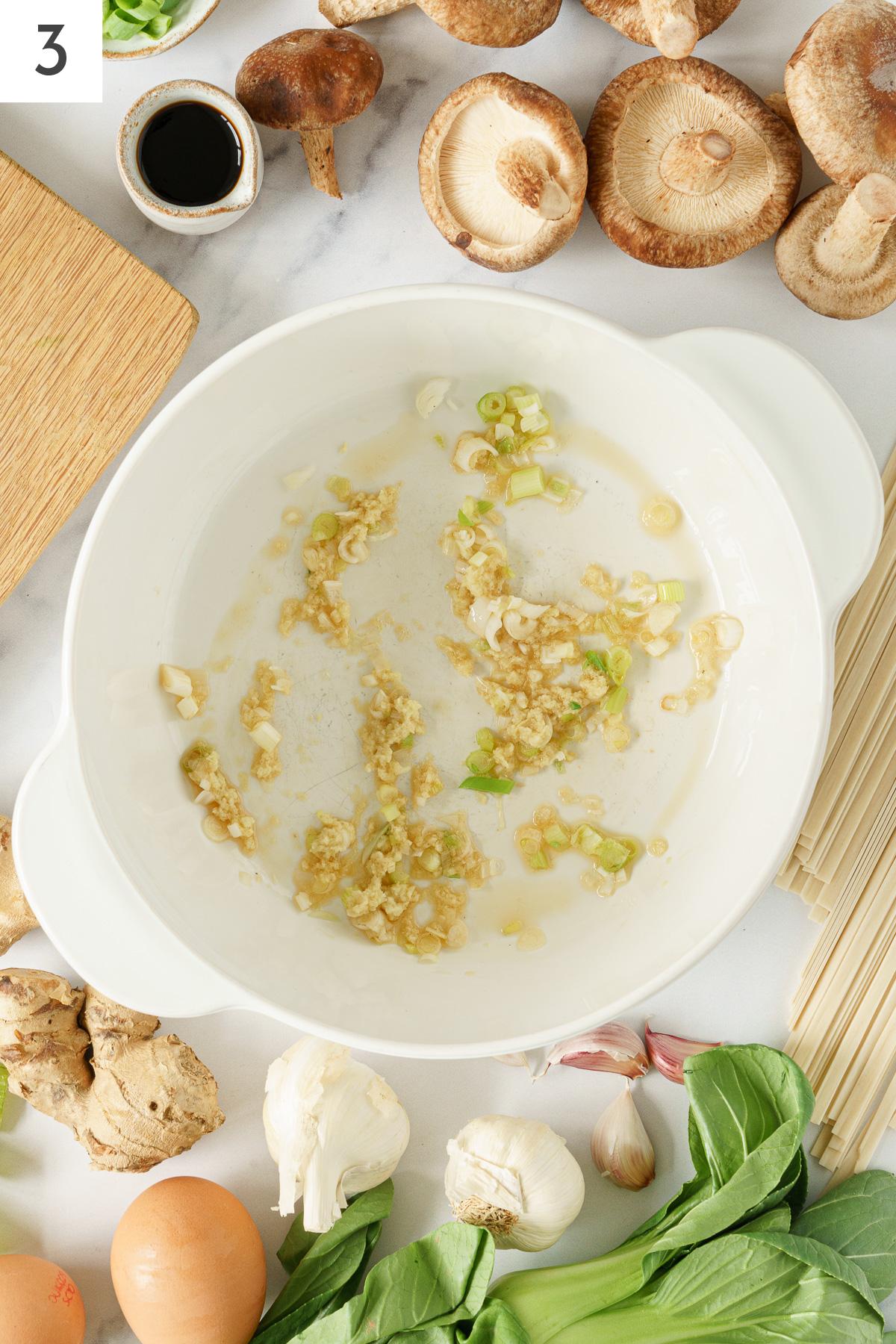 A large pot with sauteed garlic, ginger and gren onion. 