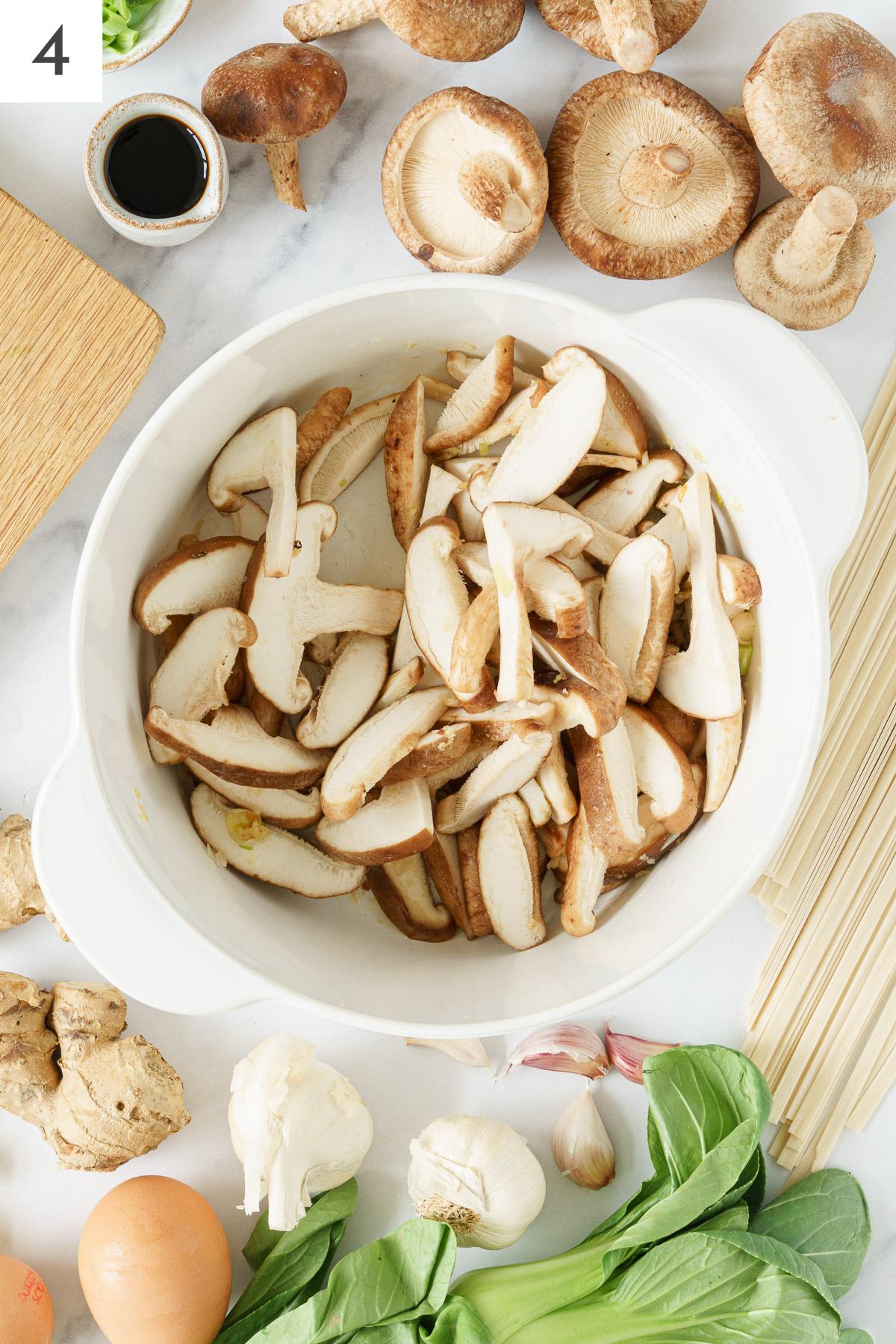 Shitake mushrooms added in a pot with sauteed spices.