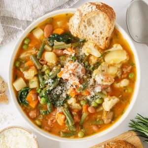 Top view of italian minestrone soup in a bowl with bread.