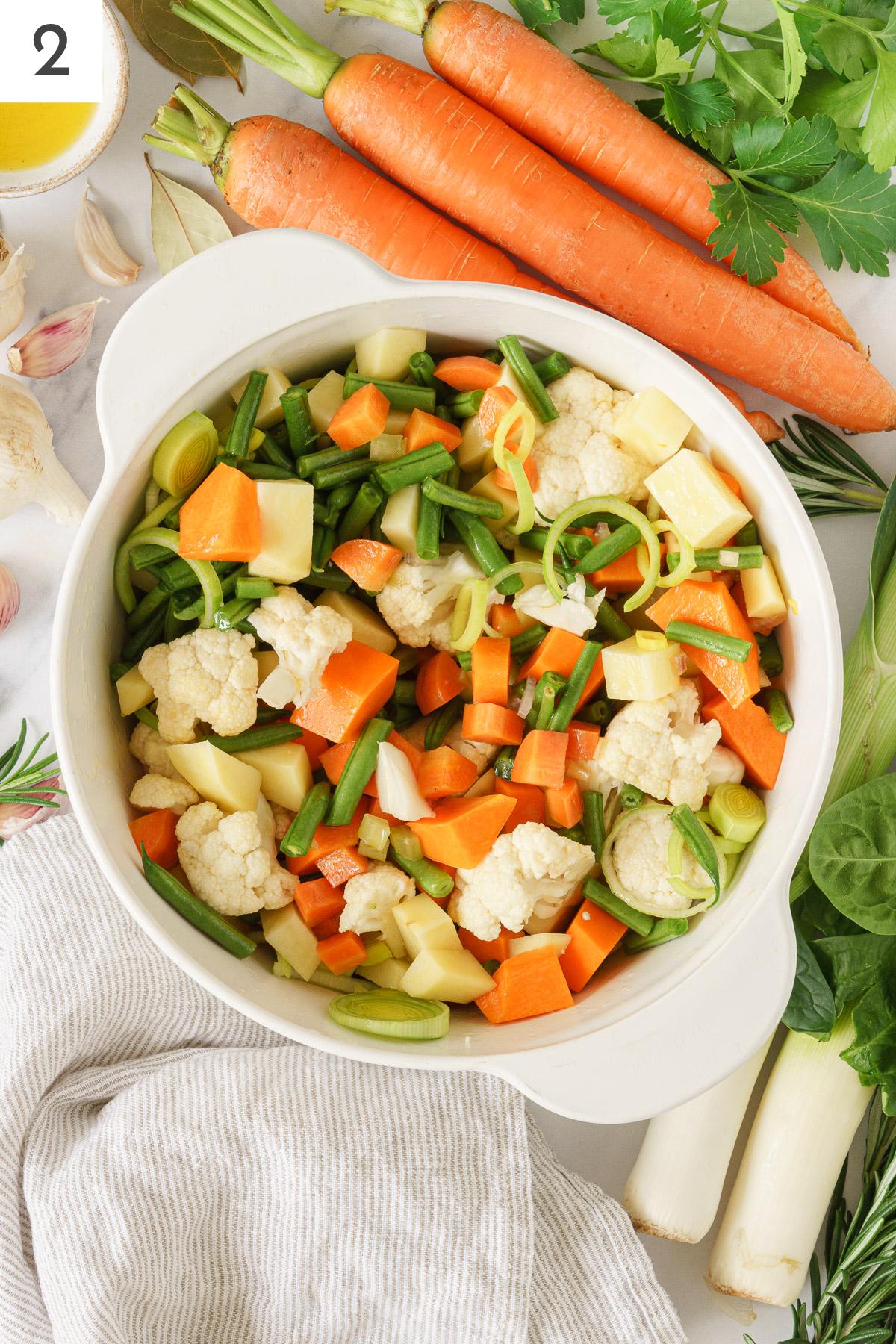 A pot with Italian minestrone soup veggies added with cauliflower, green beans, potatoes, and pumpkin.