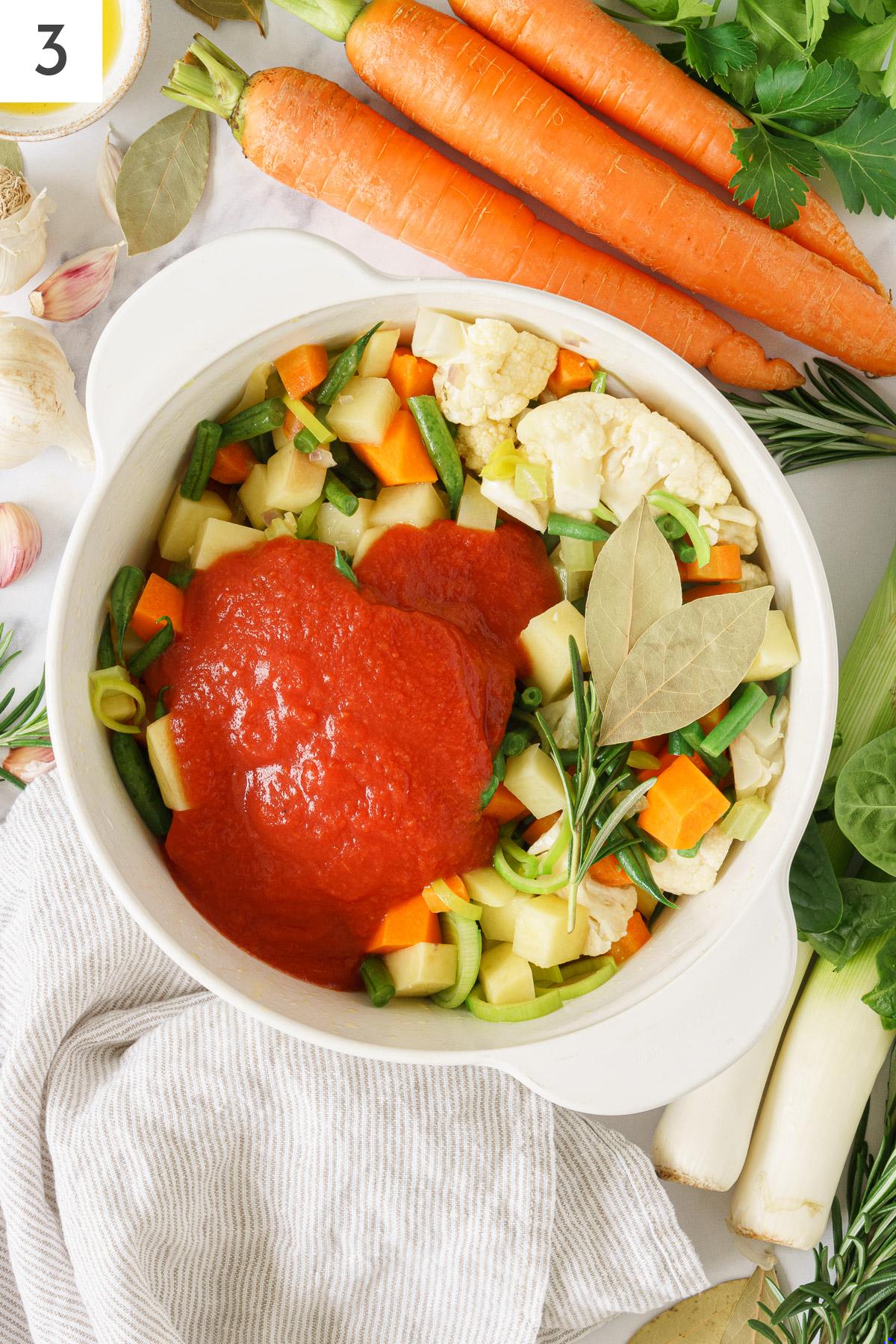 Cooking pot containing with Italian minestrone soup veggies and tomato sauce.