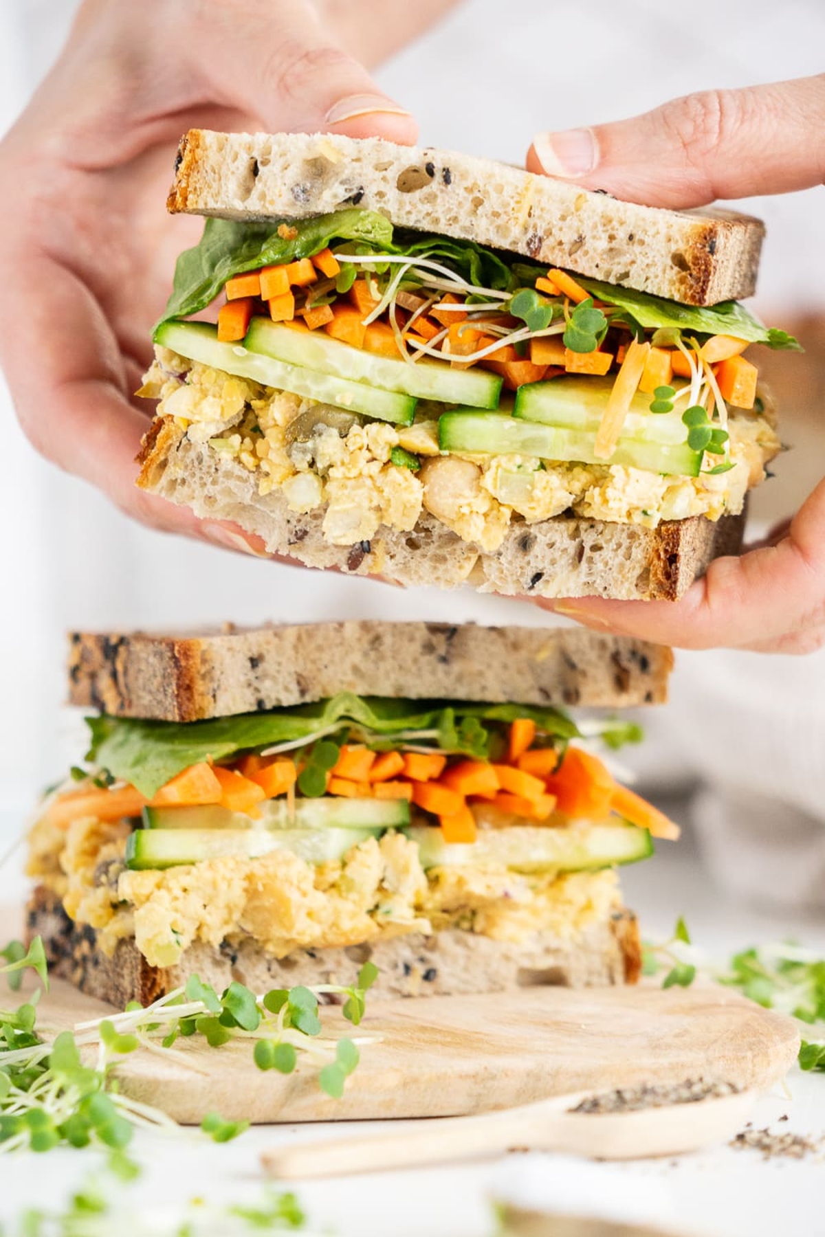 A hand holding chickpea salad sandwich.