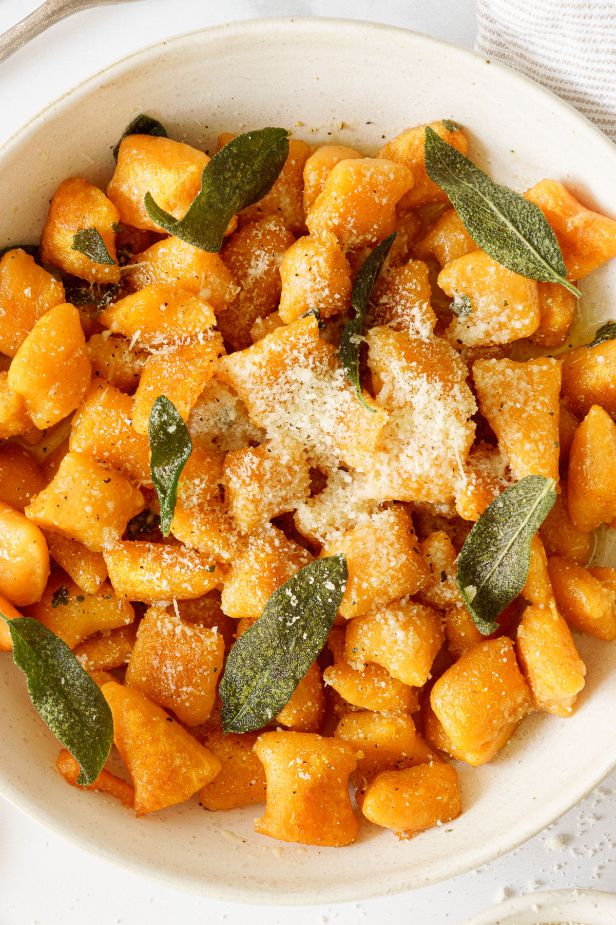 Sweet potato gnocchi in a plate sprinkled with parmesan cheese.