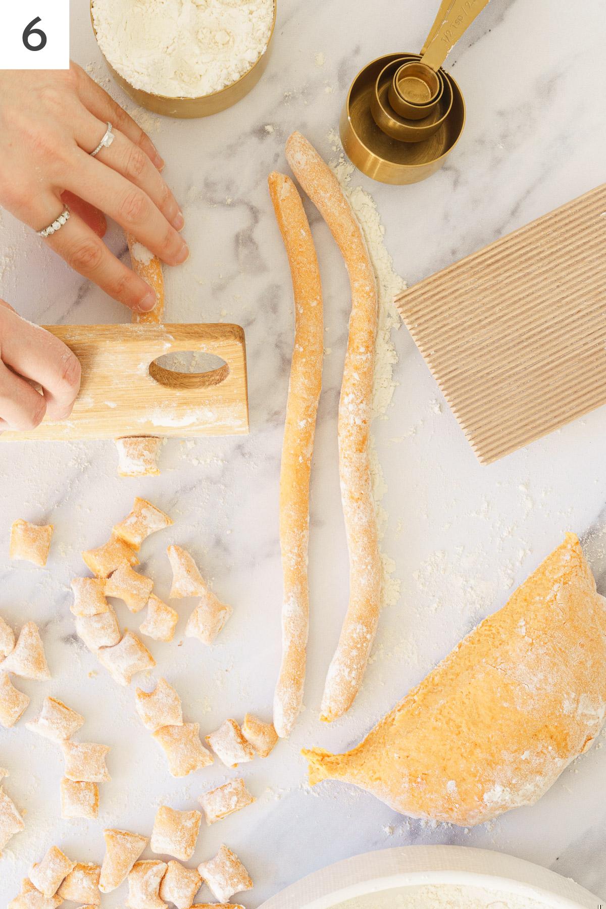 A hand cutting out the long rope dough.