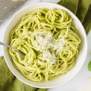 A plate of avocado pasta sauce topped with grated parmesan cheese.