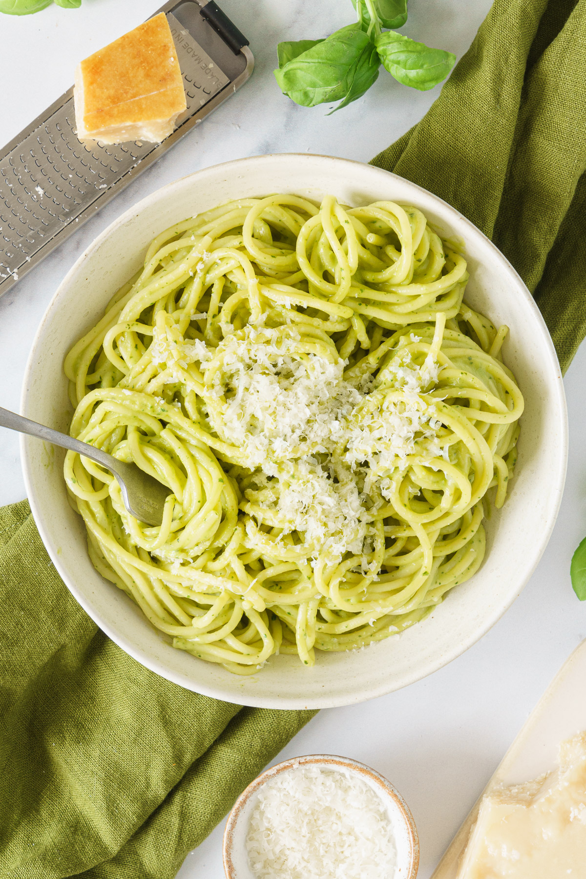 A plate of avocado pasta sauce topped with grated parmesan cheese.