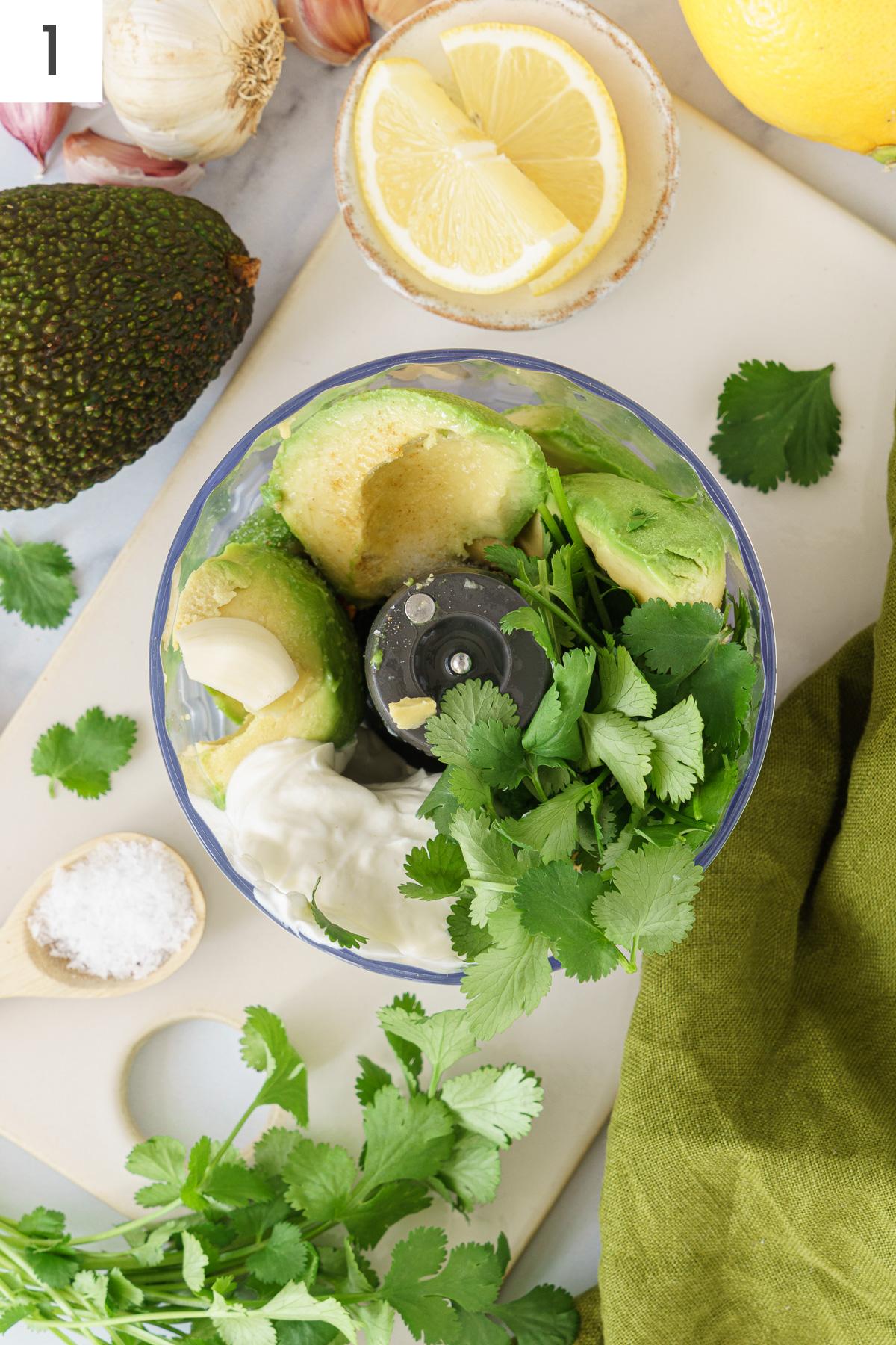 Food processor containing with avocado sauce ingredients.