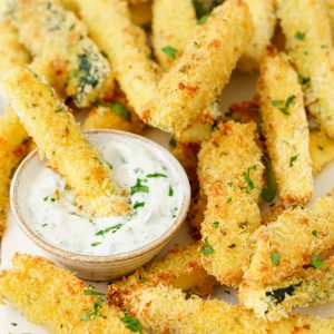 Baked zucchini sticks with dipping sauce on the side.
