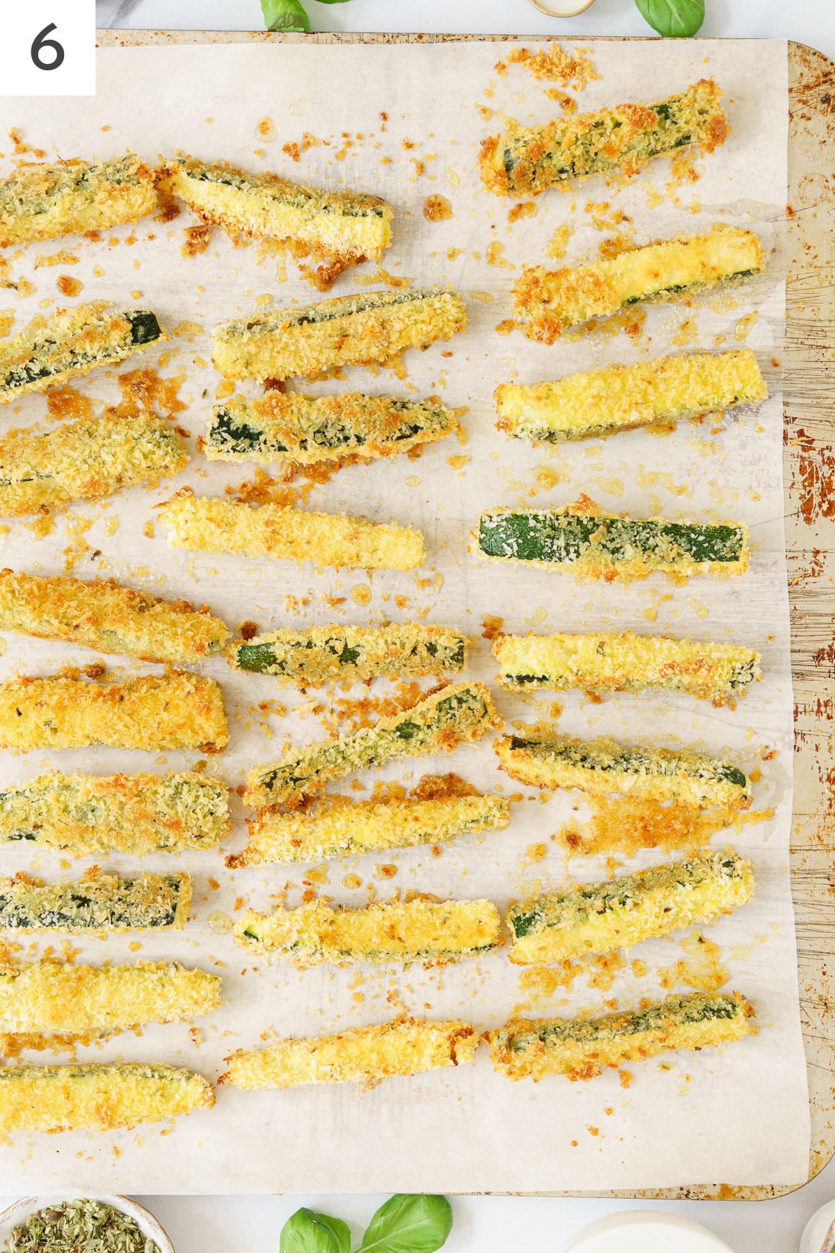 Baked zucchini sticks in a baking sheet.