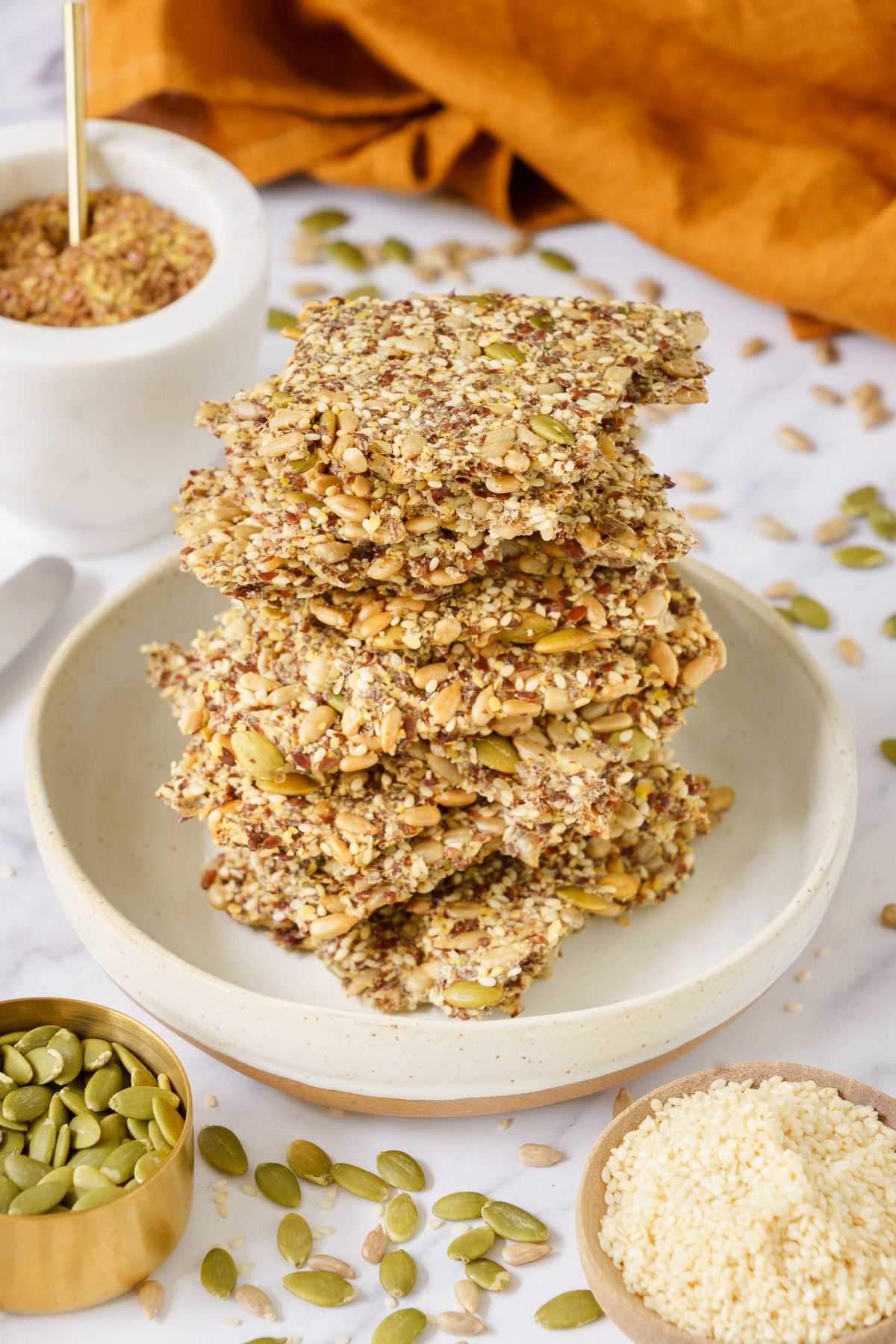 A stacked pile of seed crackers on a round plate.