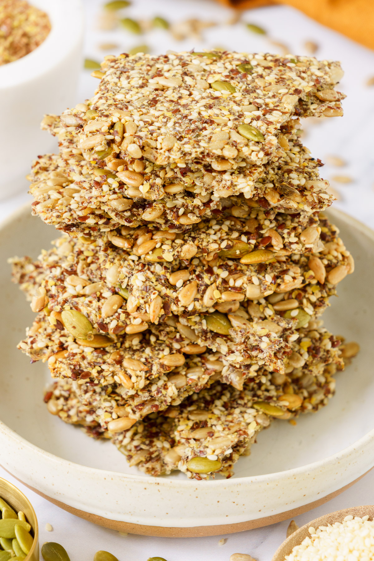 A stacked pile of seed crackers on a round plate.