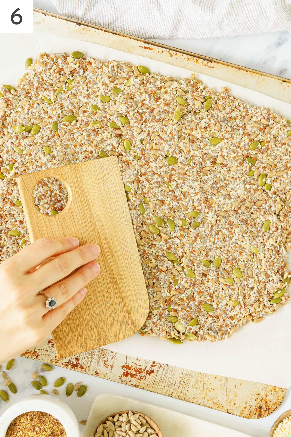 Dough like mixture of seed crackers flaten in a baking sheet.