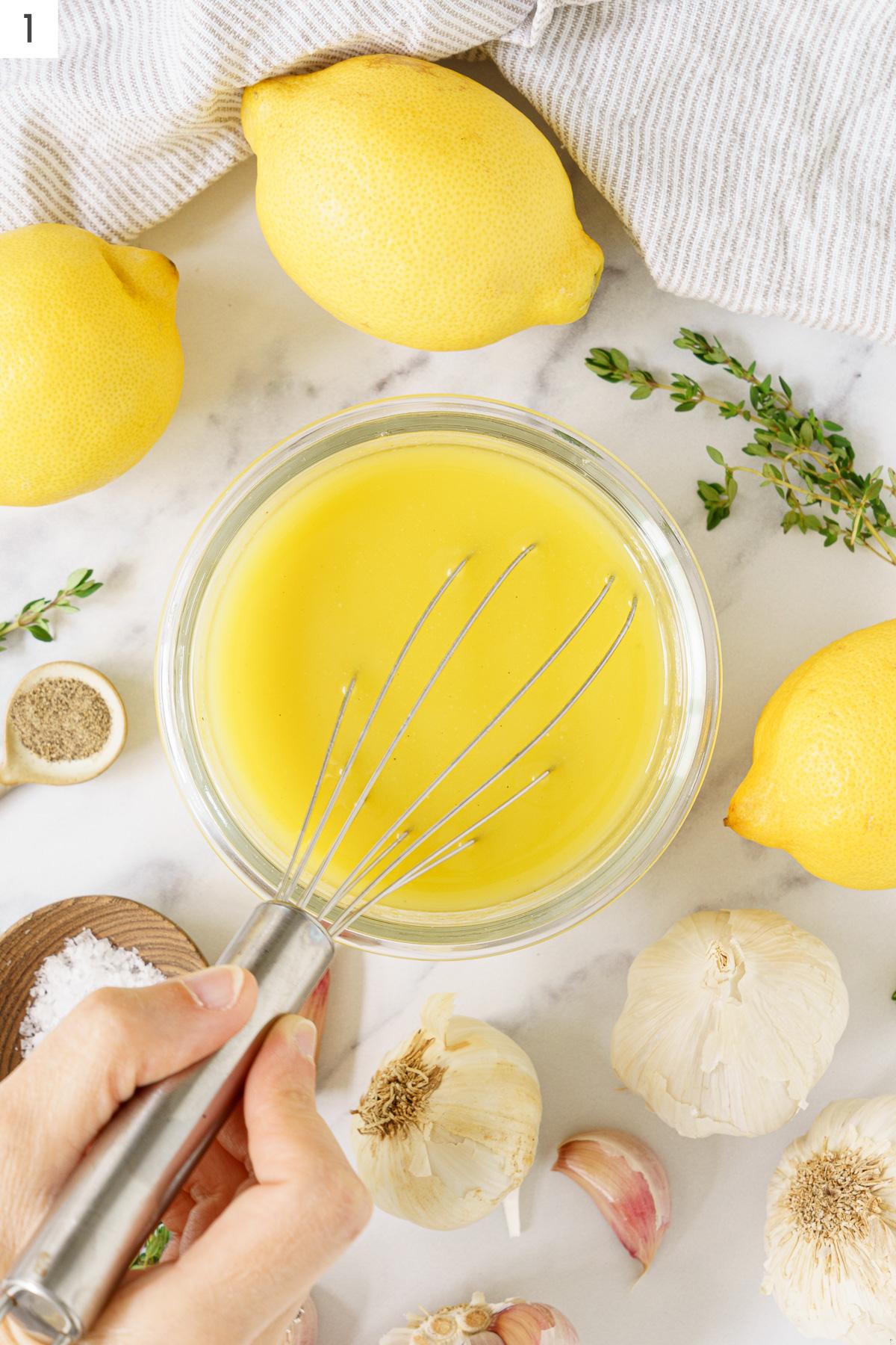 A glass container of lemon juice with a whisk.