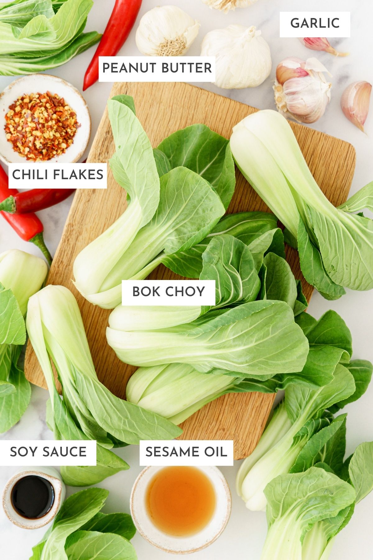 Laid out ingredients of garlic bok choy: Garlic, peanut butter,chili flakes, bok choy, soy sauce, and sesame oil.