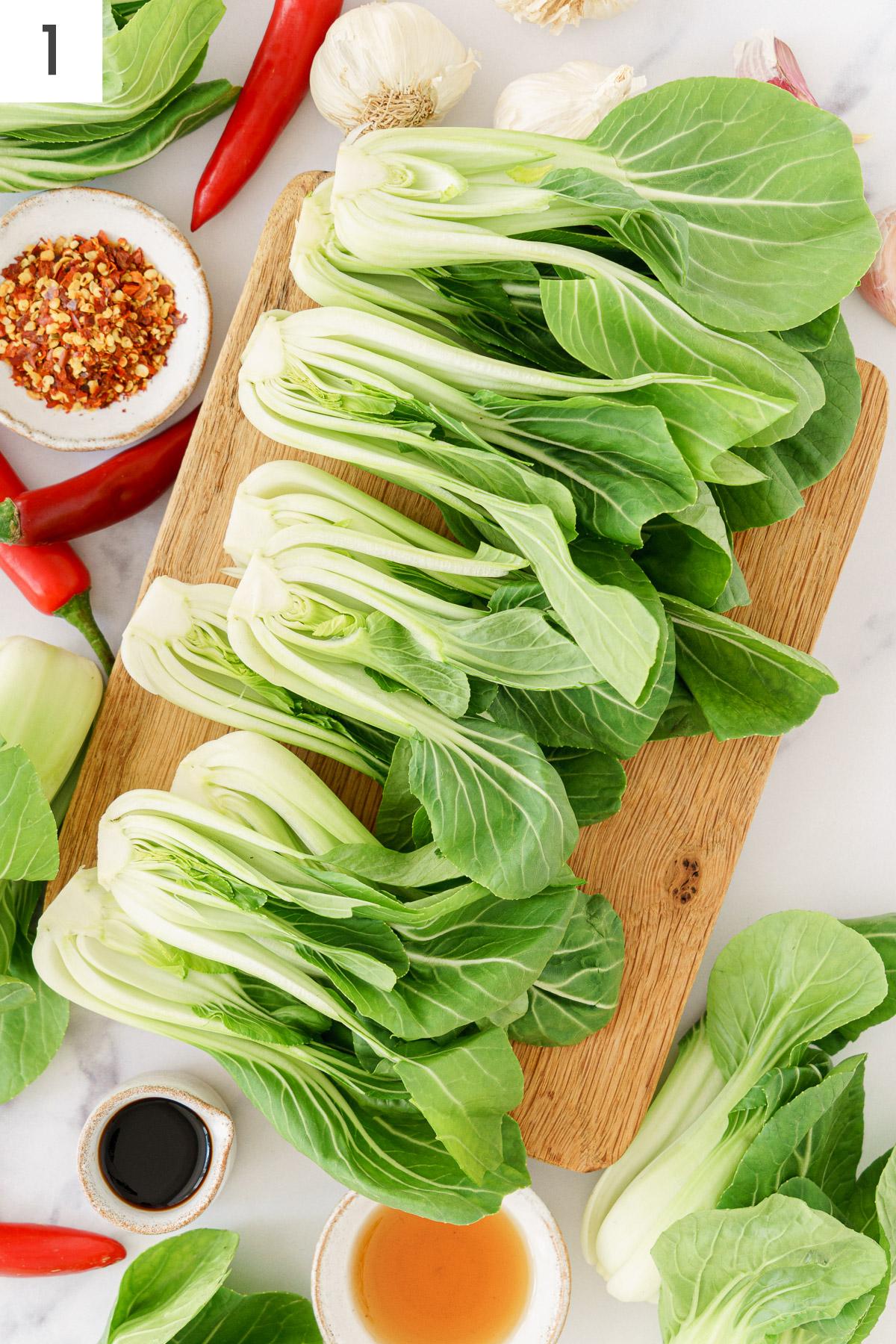 Halved bok choy on a wooden chopping board, ready for preparation.
