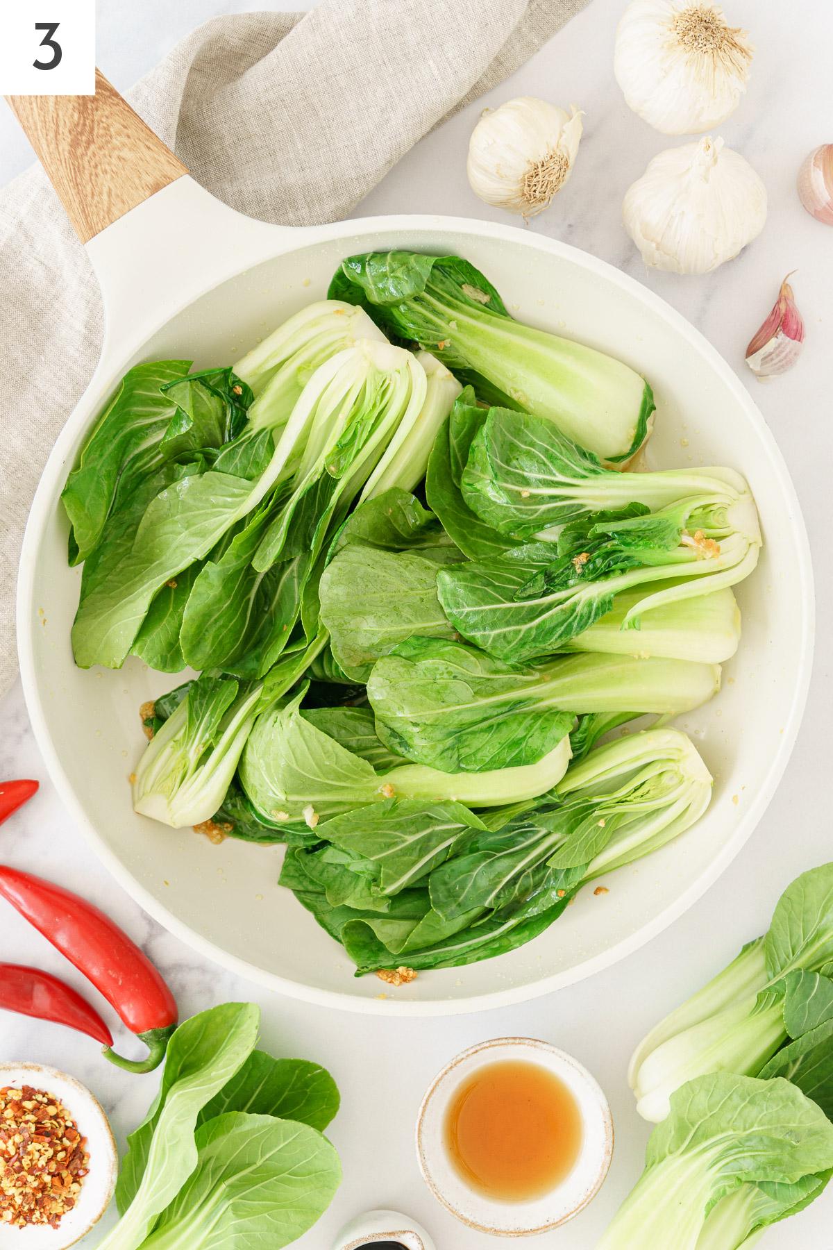 A skillet filled with sautéed chopped garlic and bok choy.
